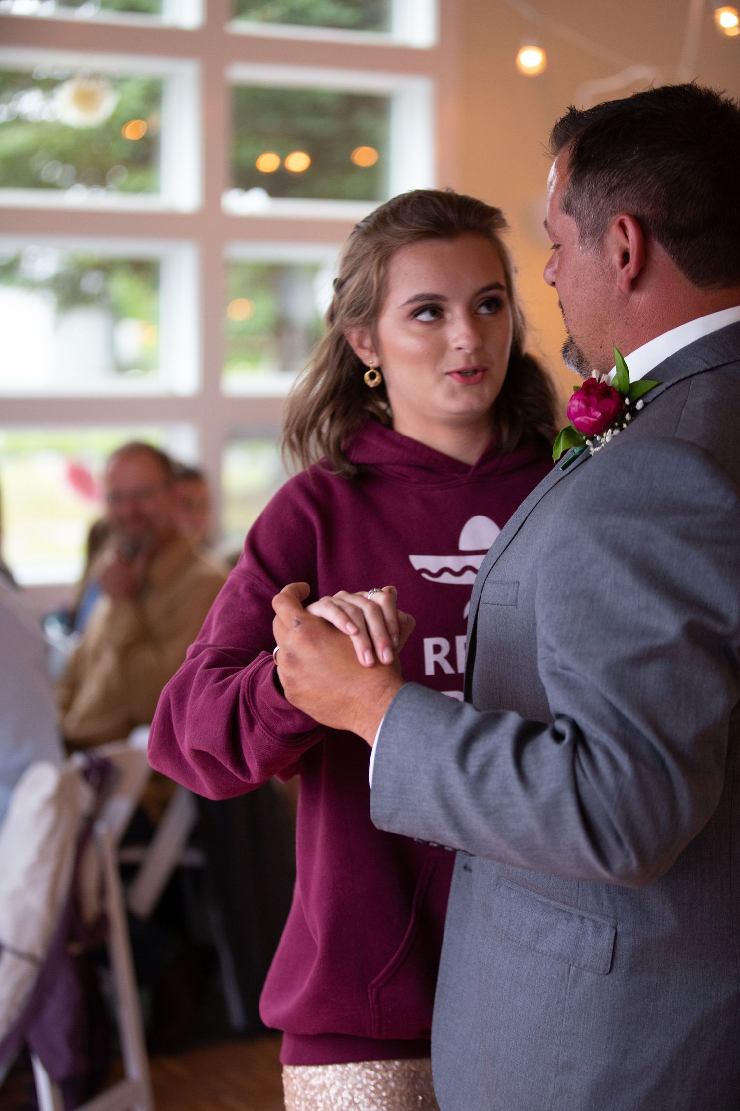 A dance between two people, one wearing a purple sweatshirt and one in formal gray attire.