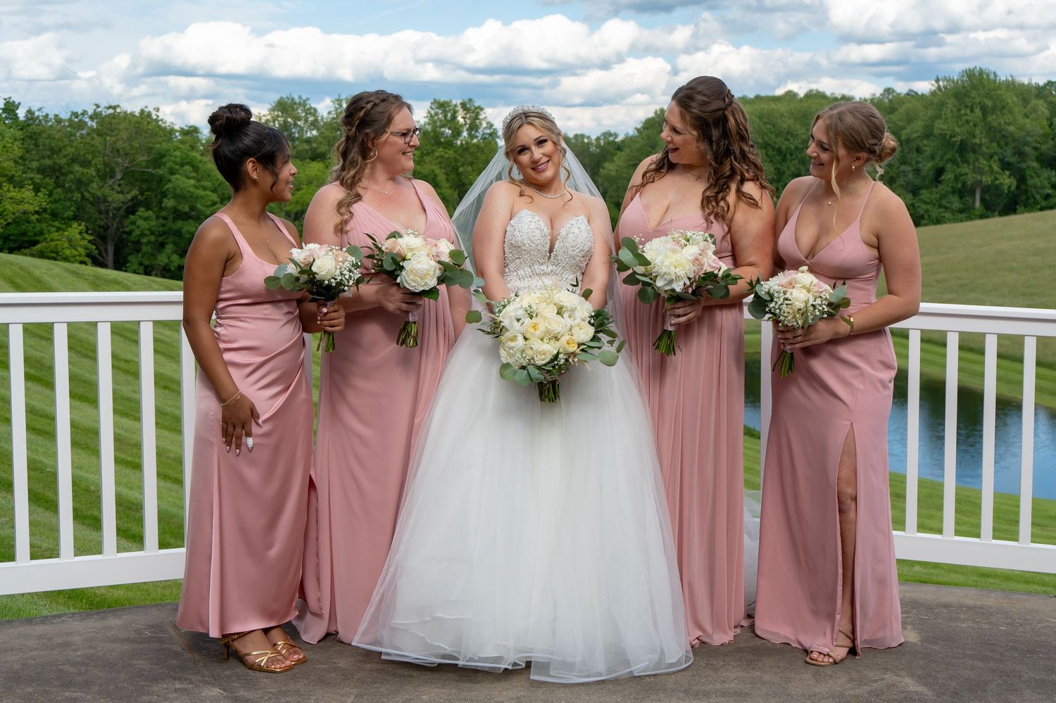 Wedding party poses on a deck with scenic rolling hills in the background.