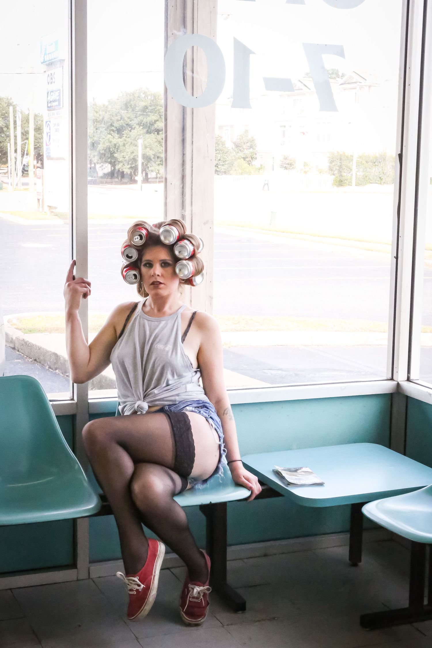 Retro laundromat setting with turquoise bench seating and large windows.