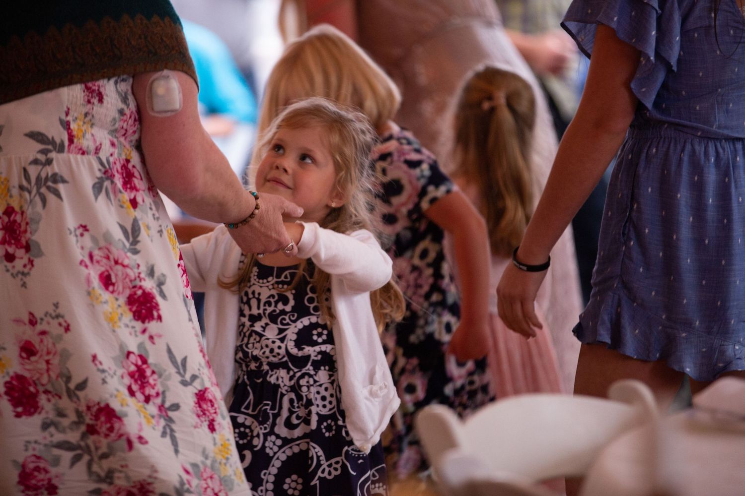 Wedding guests in floral dresses gather to celebrate during the reception.