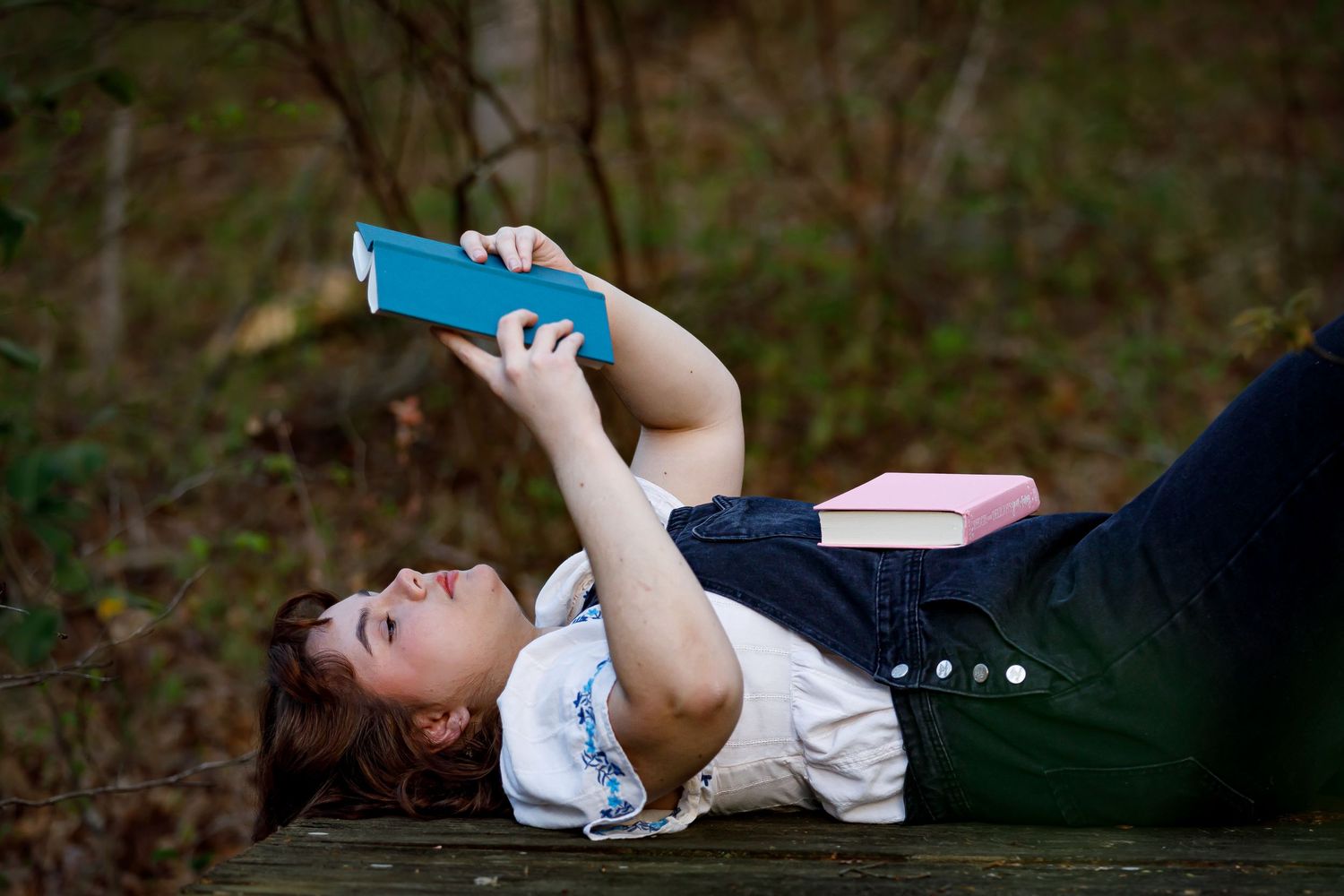 Person in casual attire lies on the ground during an artistic outdoor photoshoot.