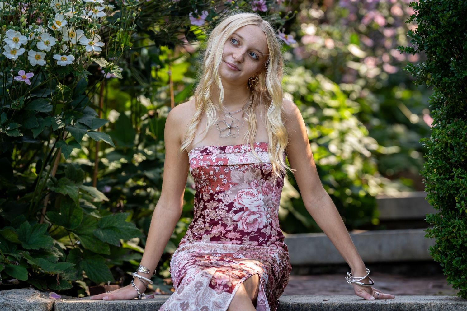 Garden portrait session surrounded by pink and white flowers.