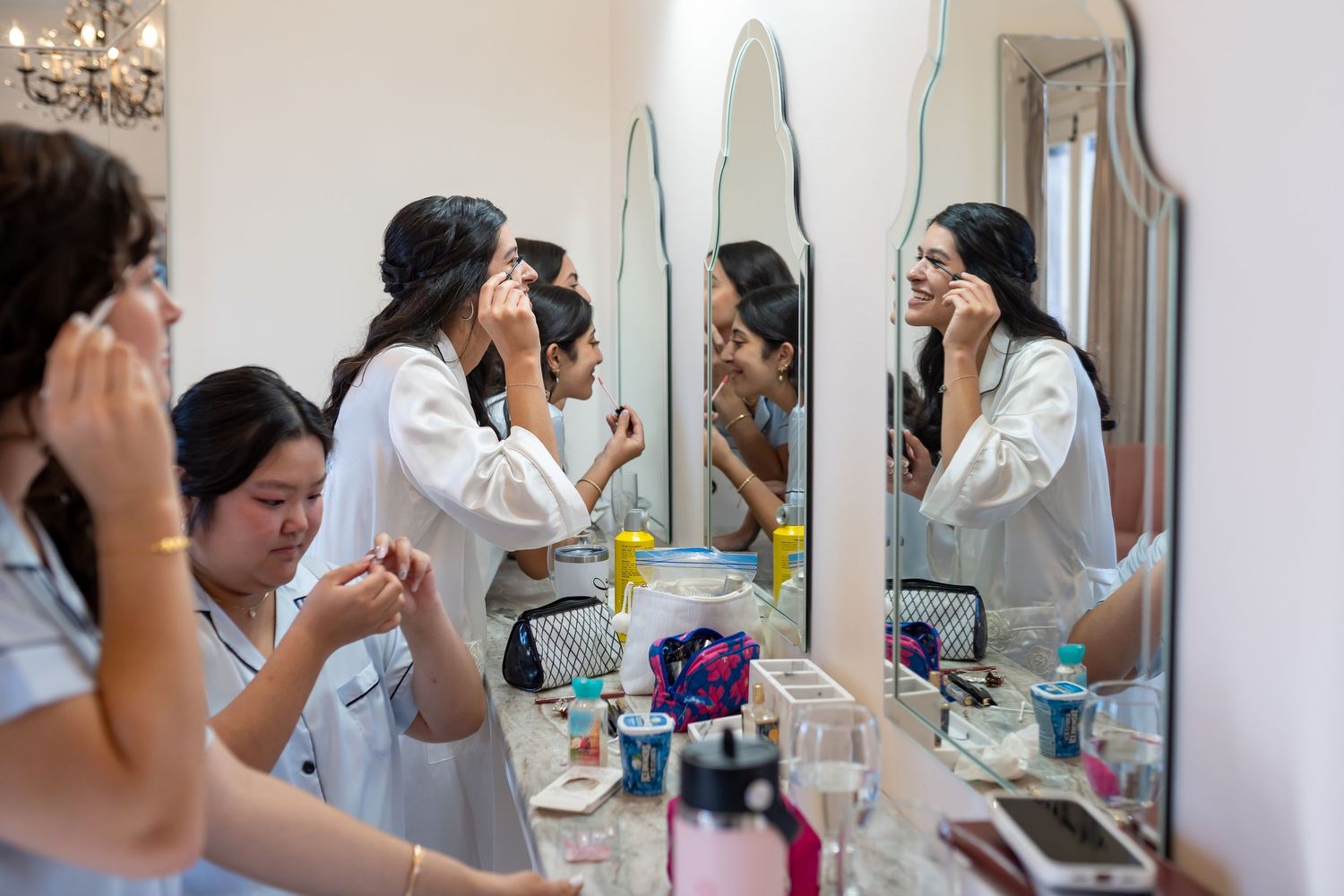 Wedding preparation scene with people getting ready at a vanity mirror station.