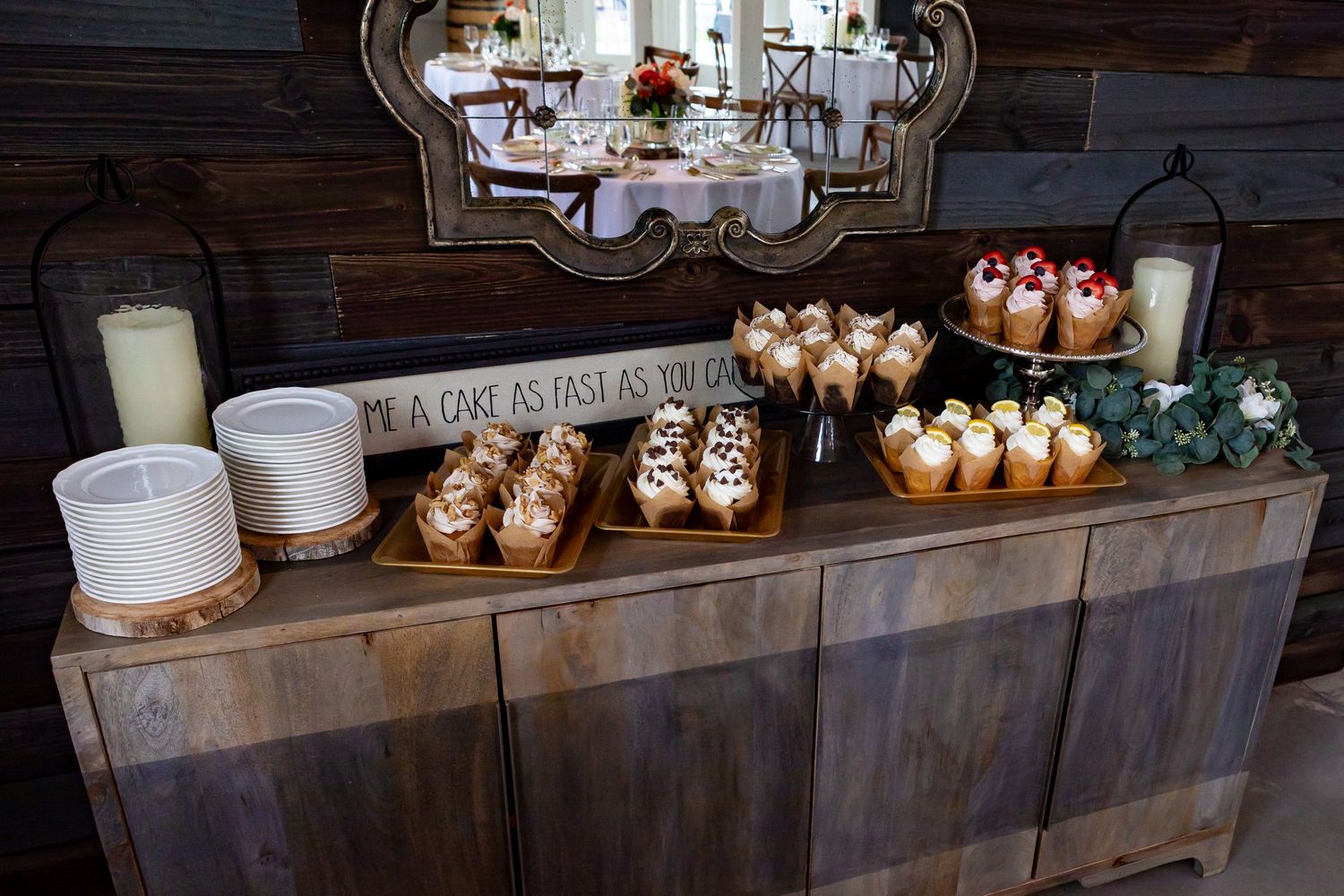 Elegant dessert display with candles and treats on wooden shelving.