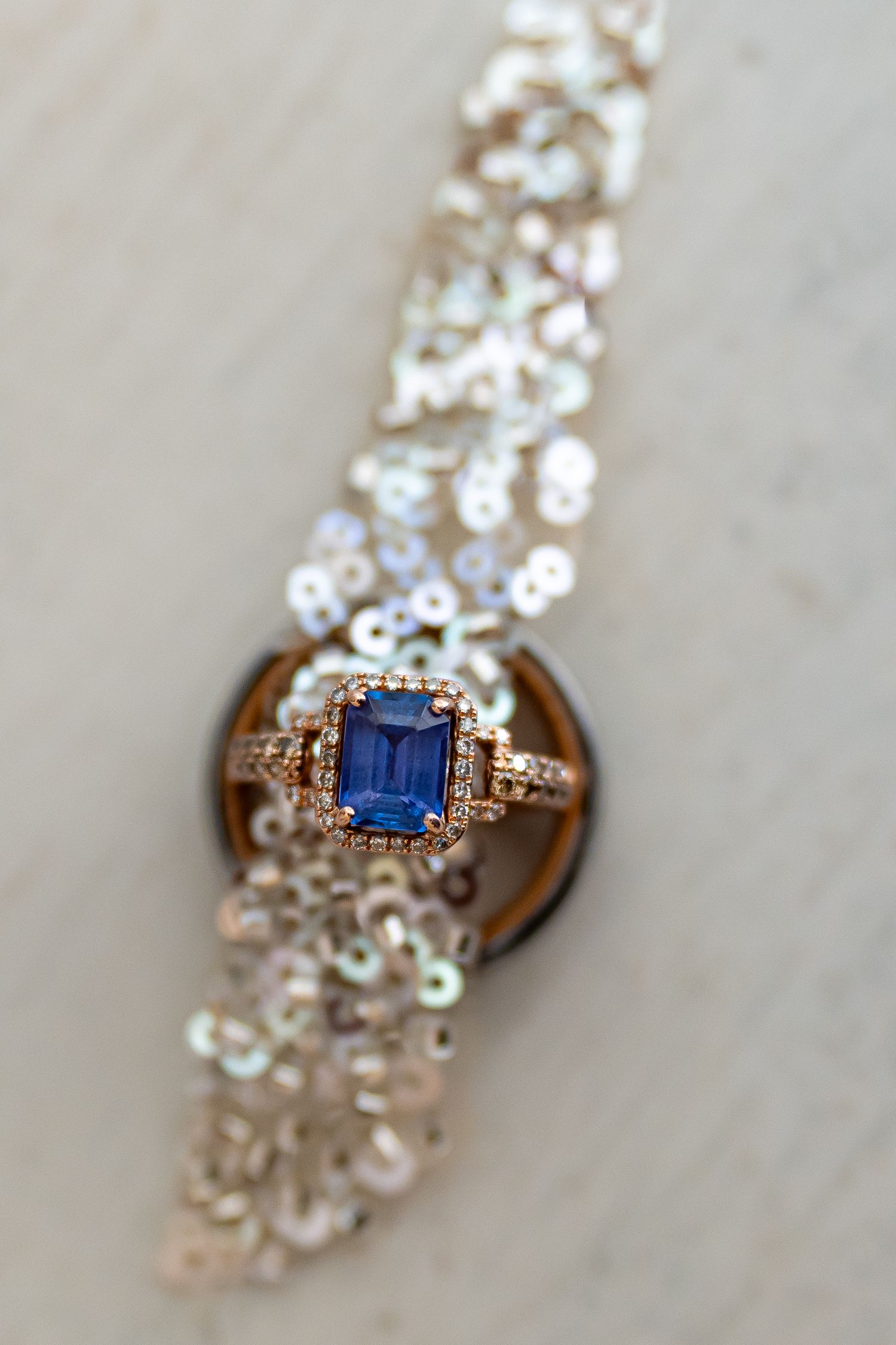 Close up of a sapphire and diamond engagement ring in rose gold setting.