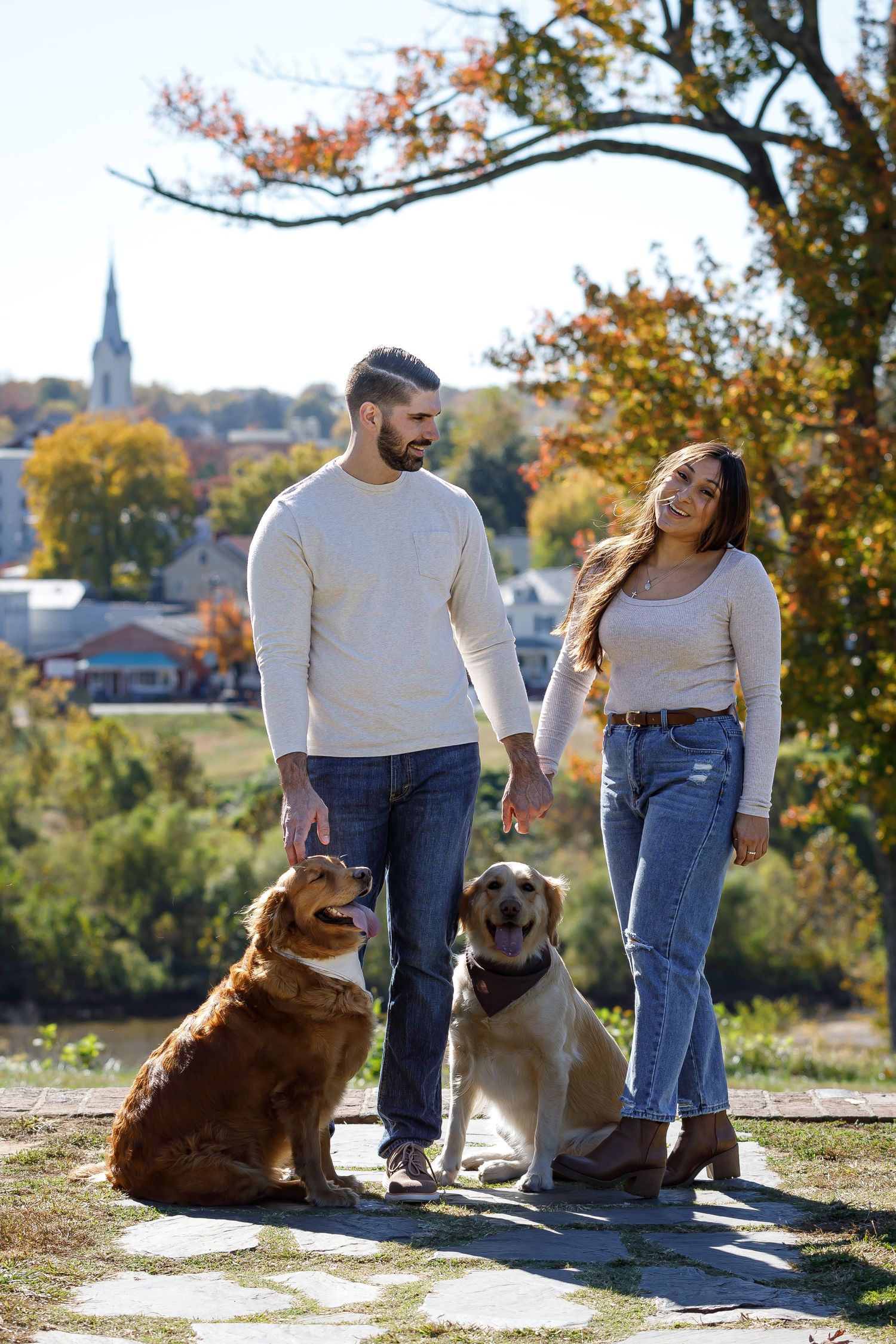 Couple with two dogs enjoying an autumn day with city skyline in background.