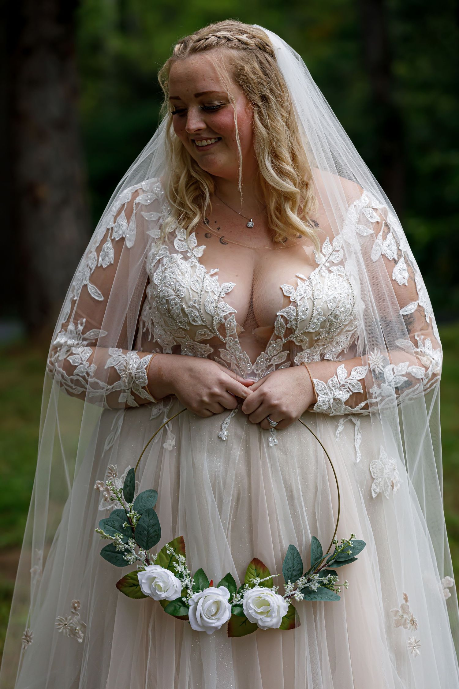 Beautiful bride in lace sleeve wedding gown with floral details and long veil.