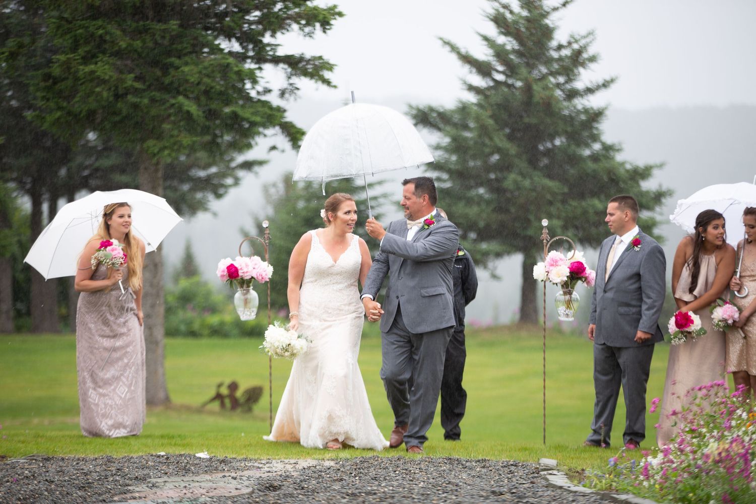 Wedding party walking across a green lawn on an overcast day.