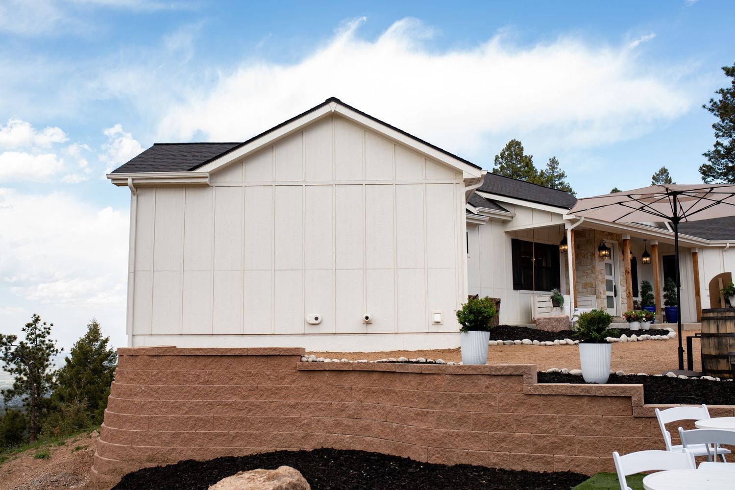 Modern white farmhouse exterior with brown landscaping and steps leading to covered porch.