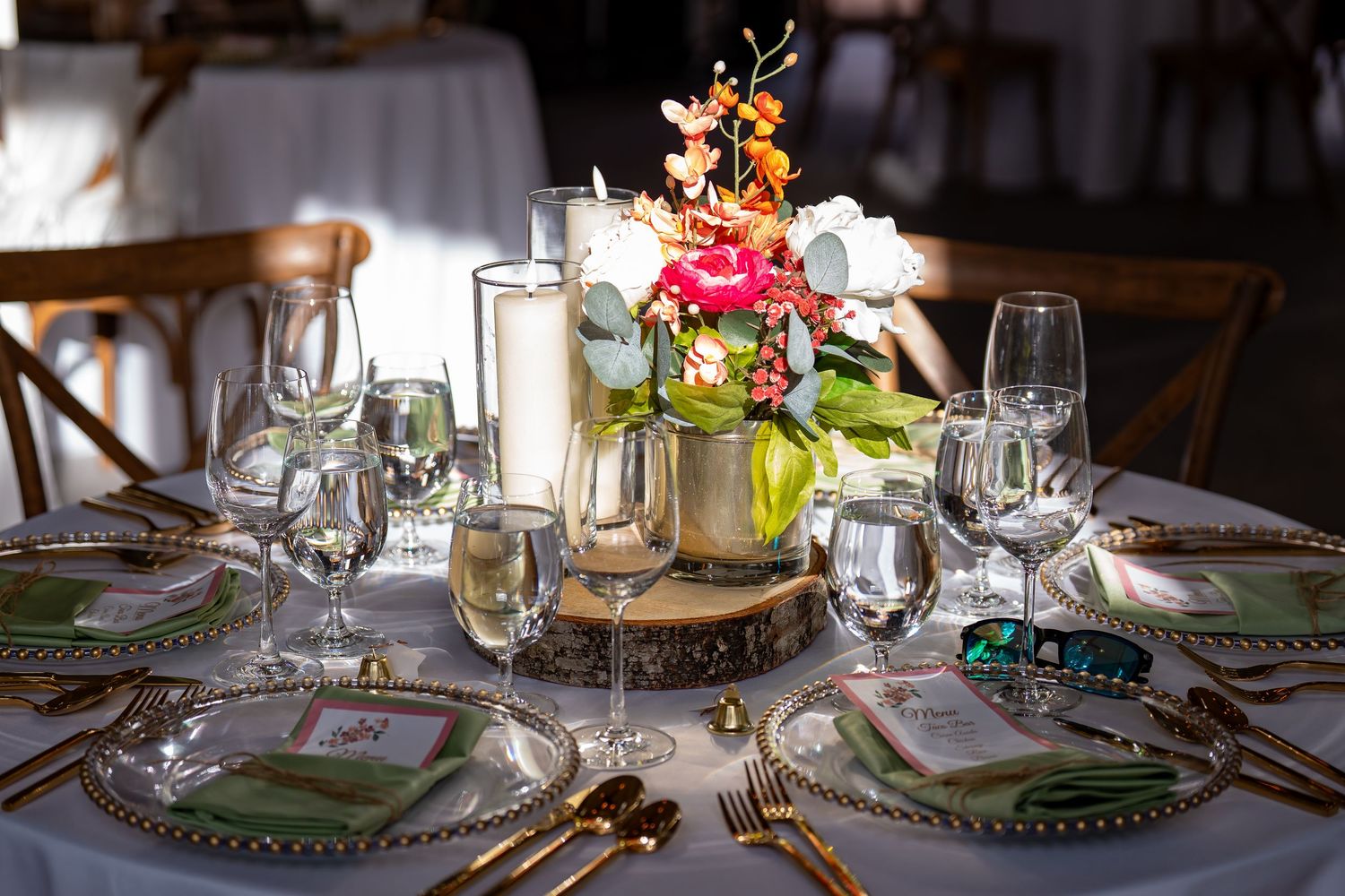 Round dining table with vintage place settings, crystal glassware and colorful floral centerpiece arrangement.