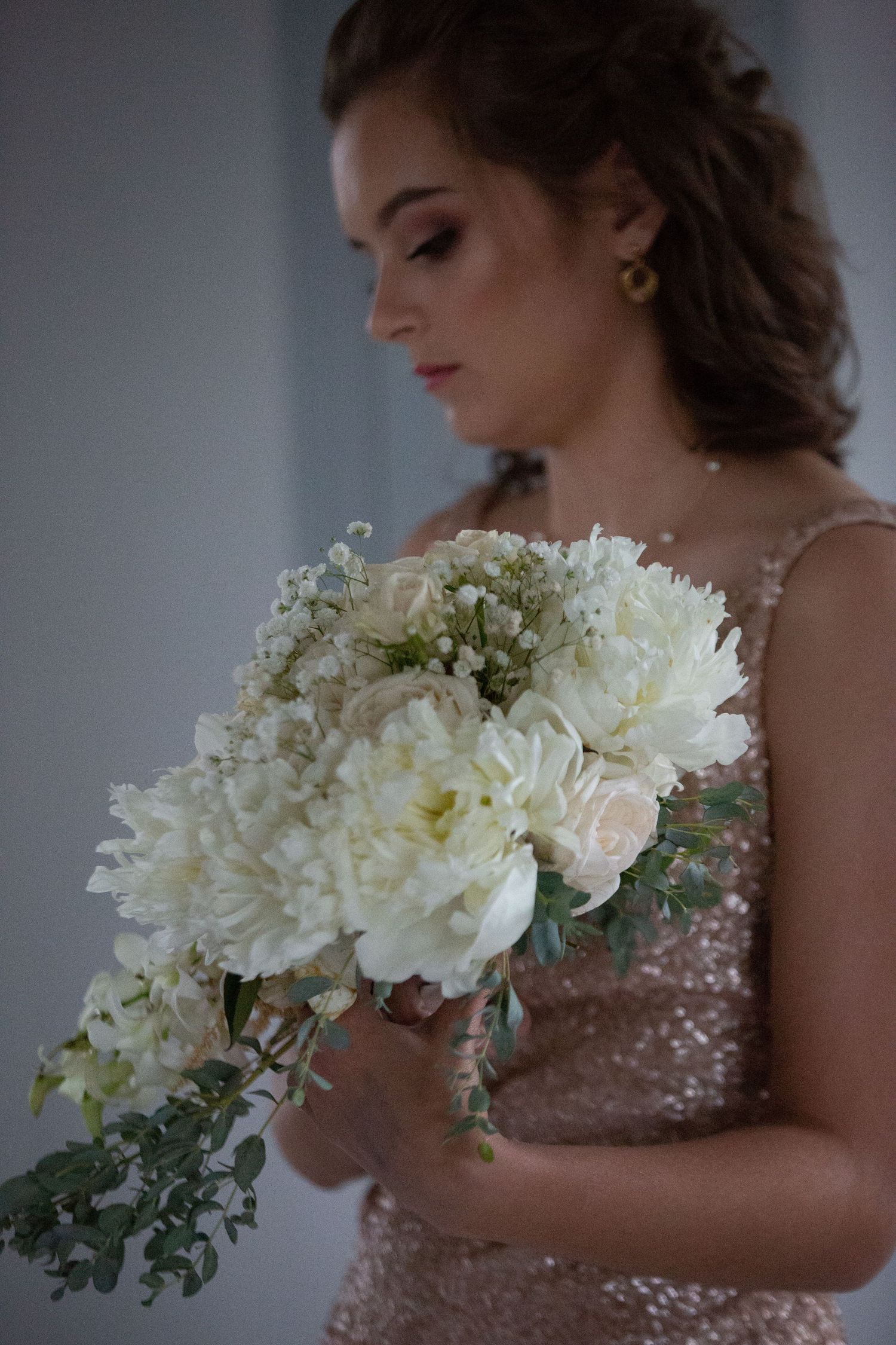 Close up of a white peony bouquet against a sparkly blush pink dress.