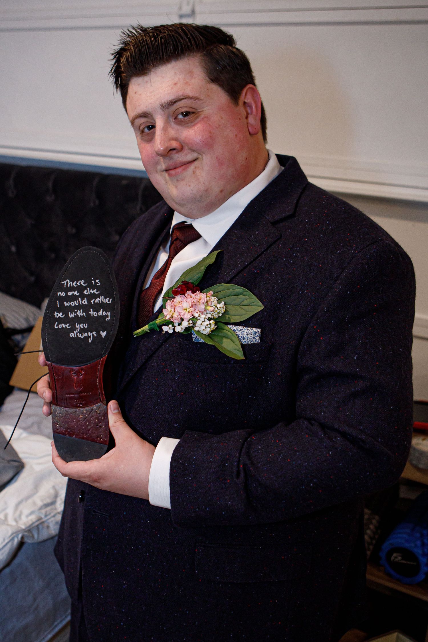 Person in formal suit holding a decorated item with a boutonniere.