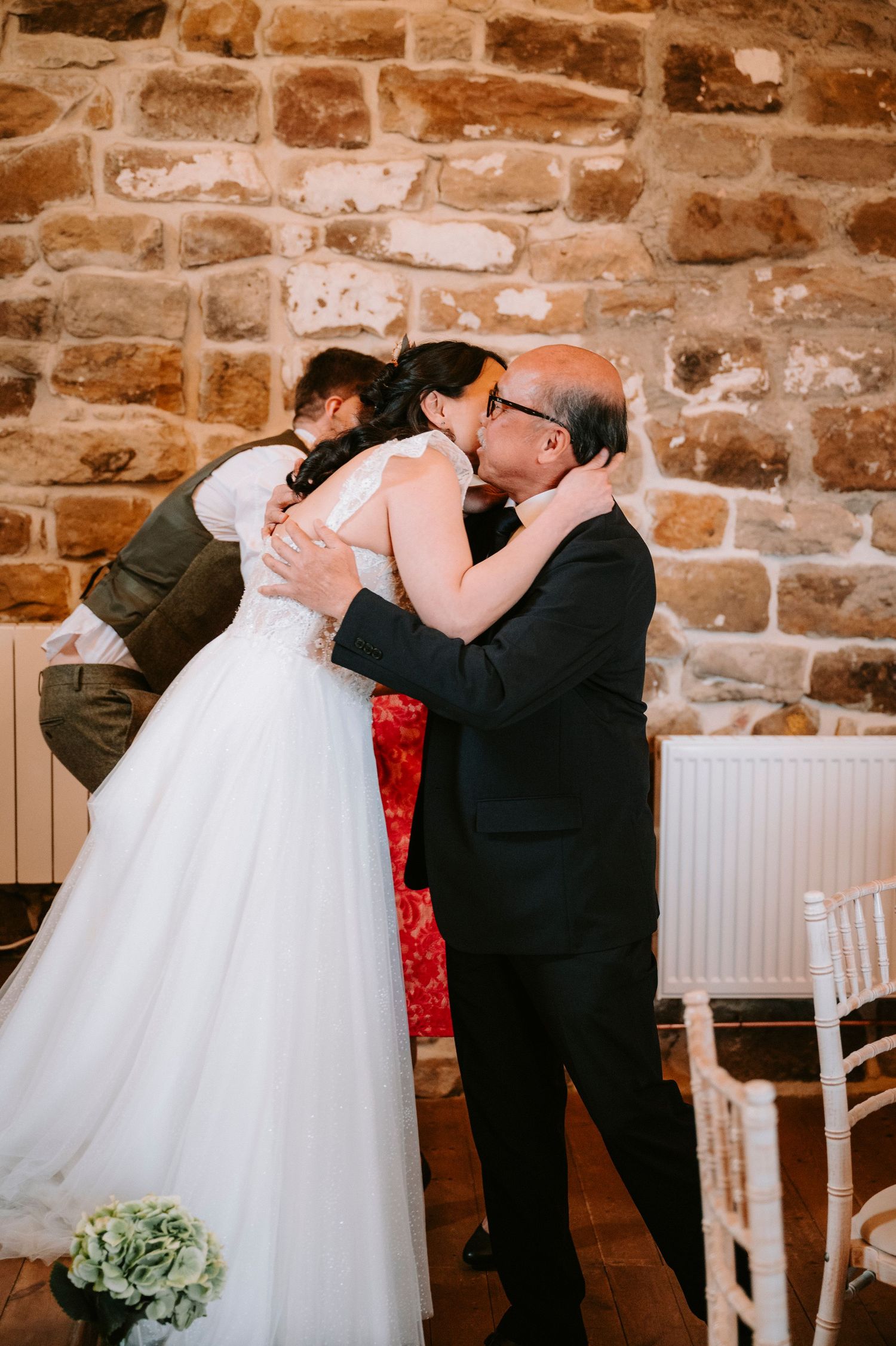 A touching dance moment captured at a wedding reception in a rustic stone venue.