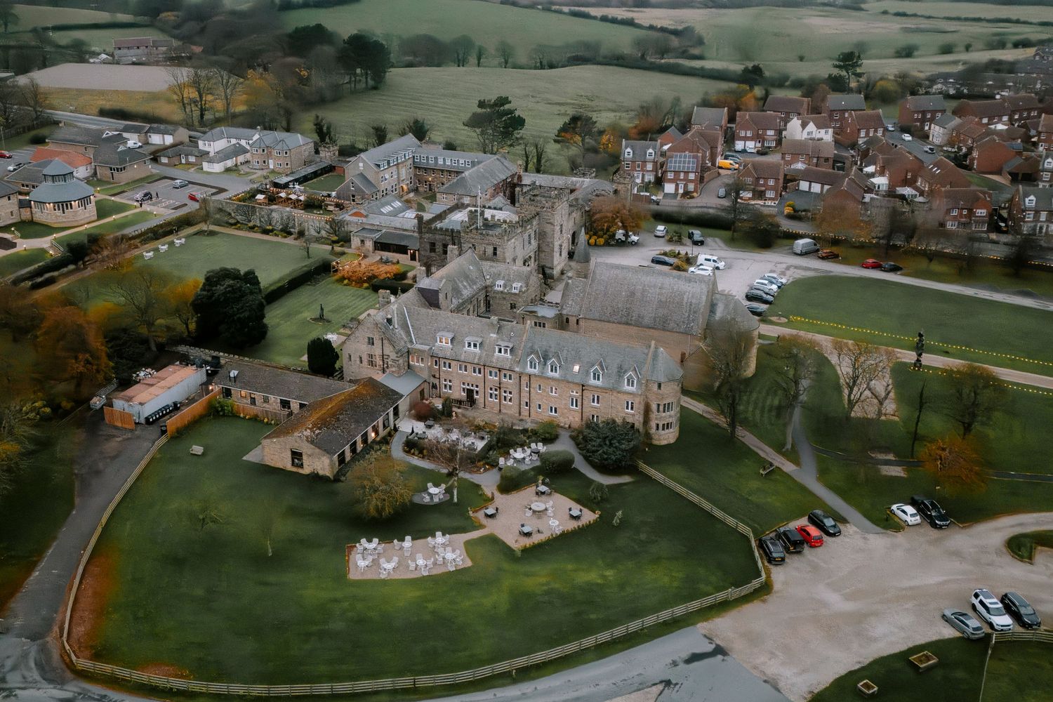 Aerial view of a grand estate surrounded by manicured lawns and countryside.