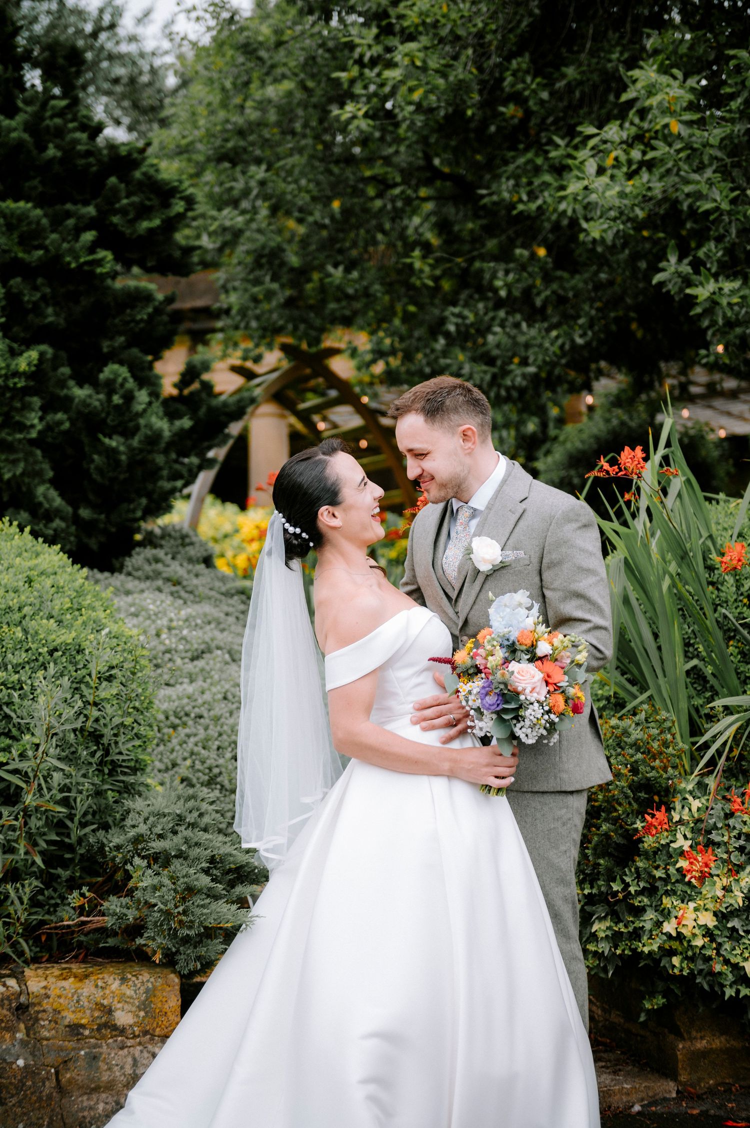 Romantic garden wedding portraits with colorful floral bouquet against lush greenery.