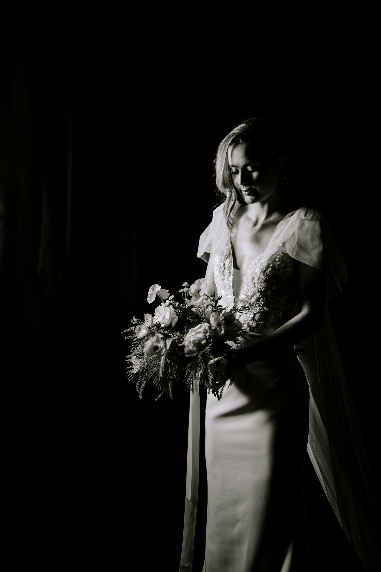 Artistic black and white composition of wedding dress details and bouquet.
