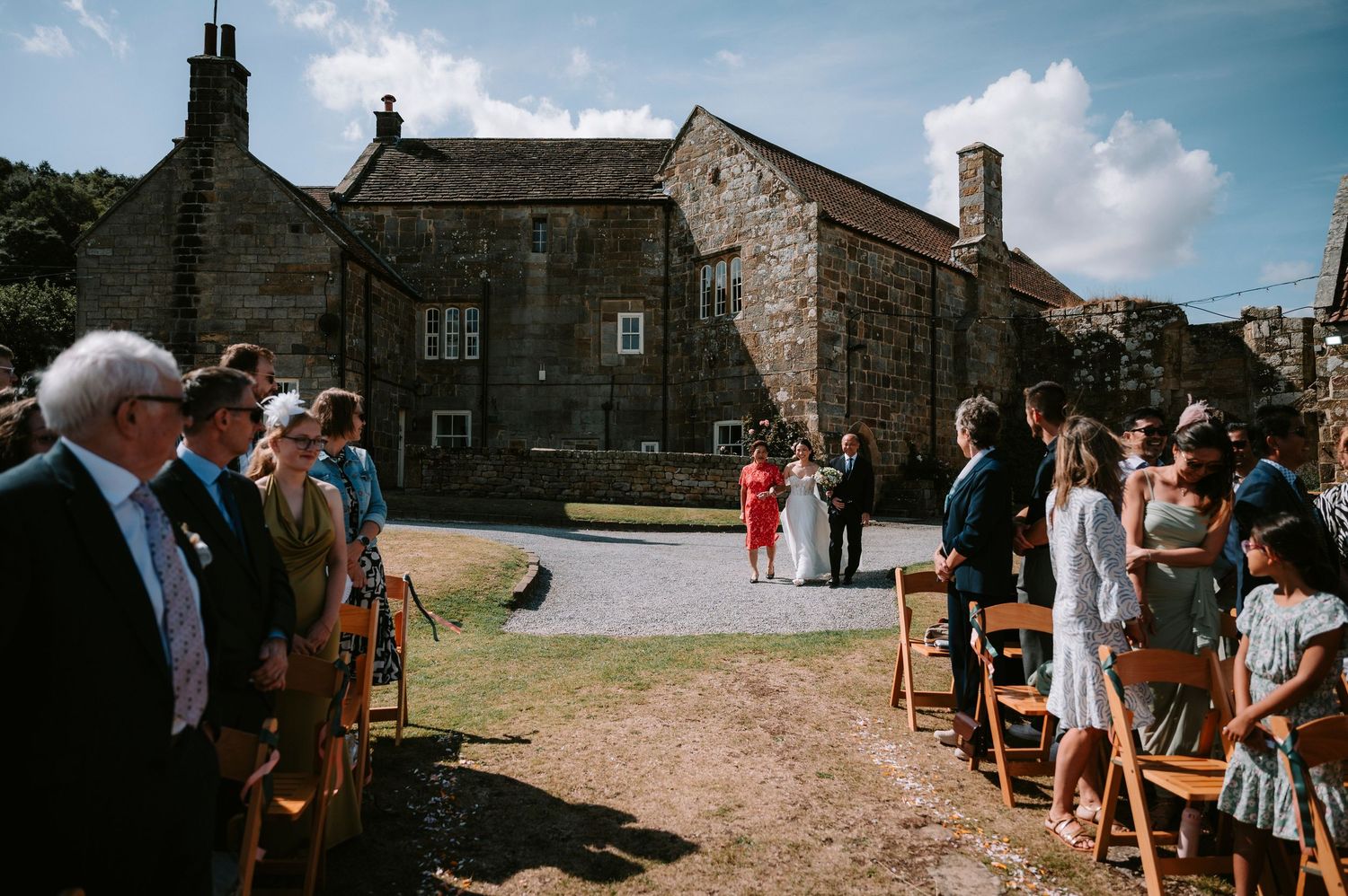 Outdoor wedding ceremony setup with chairs and stone buildings in background.