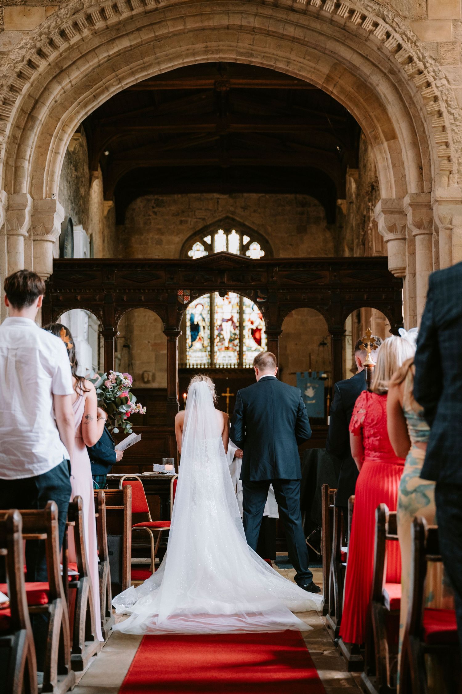Interior view of a church wedding ceremony with stone archways and a red carpet aisle.