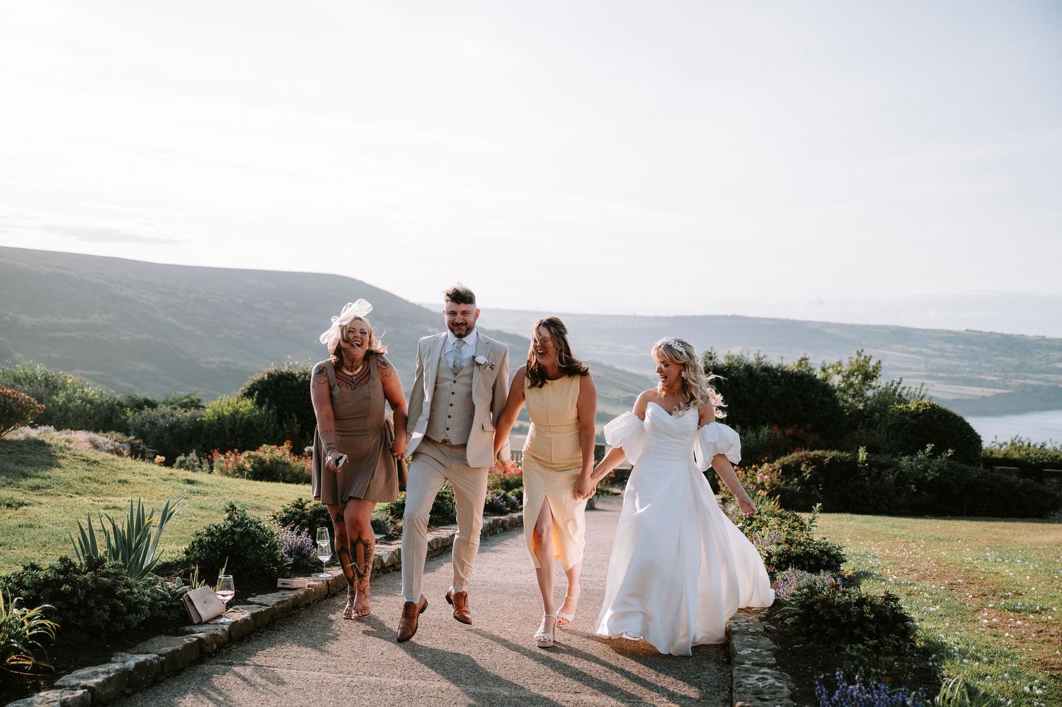 Scenic coastal wedding celebration with guests walking along a cliff overlooking the ocean.