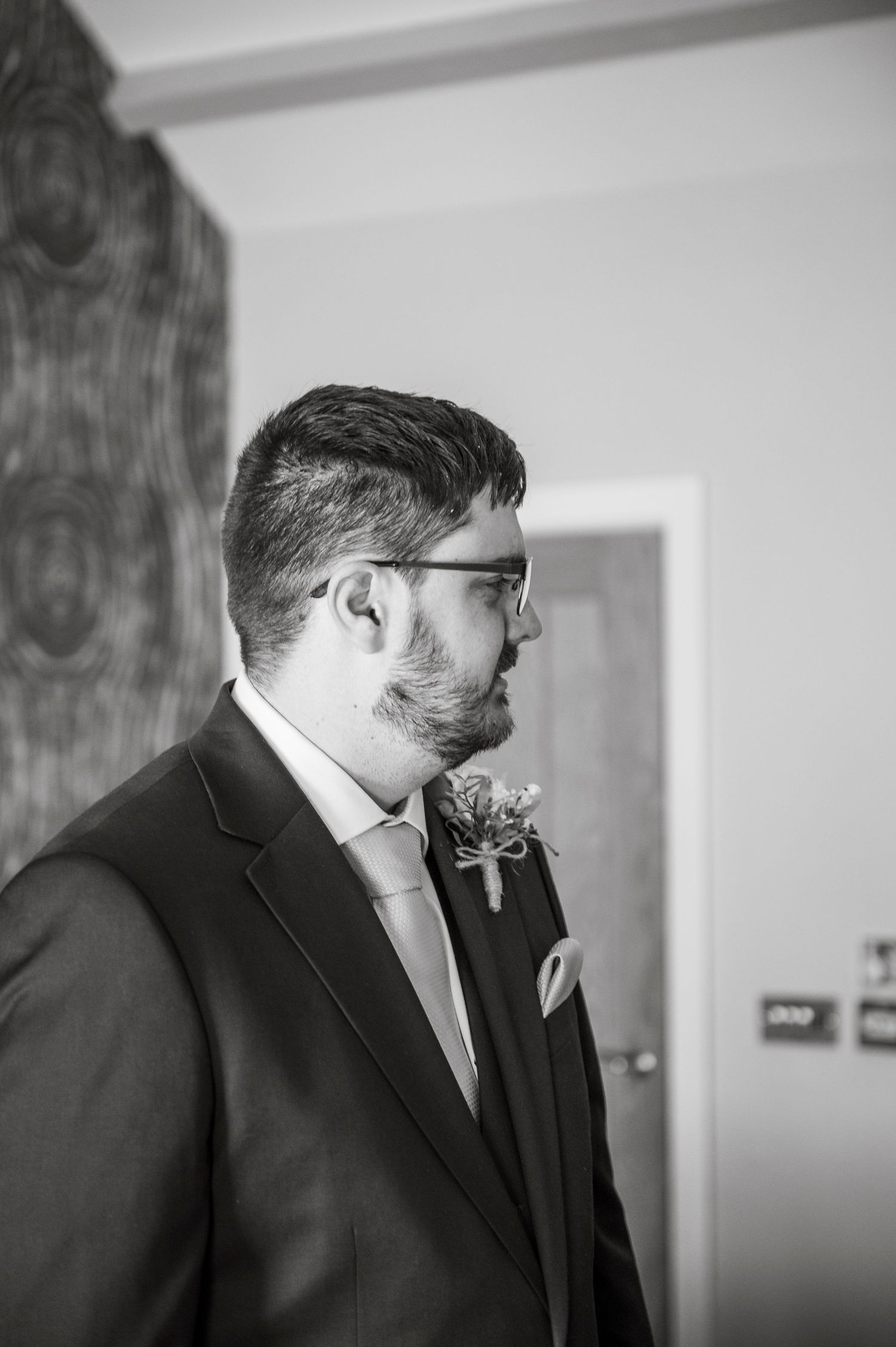 Wedding party members in dark suits prepare for ceremony in elegant indoor setting.