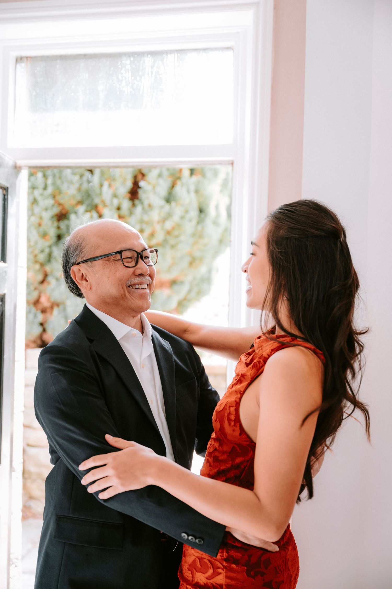 Emotional moments shared between wedding attendees in formal attire against a bright interior backdrop.