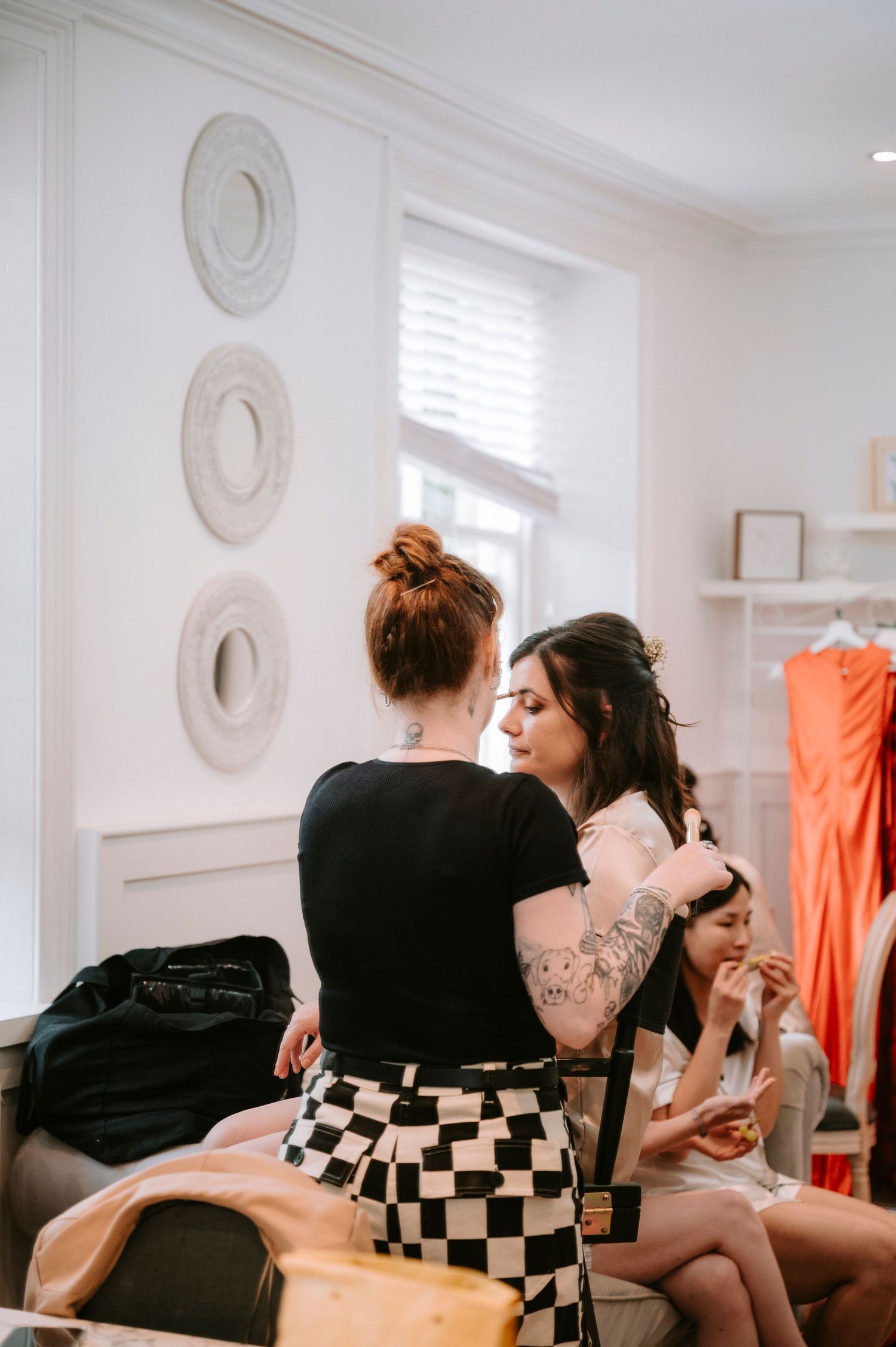 Wedding preparation scene in a bright white room with decorative circular wall art.