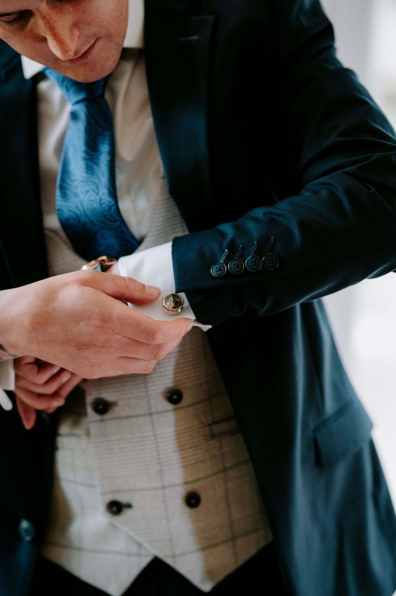 Close-up shot of hands adjusting formal wear cufflinks and buttons.