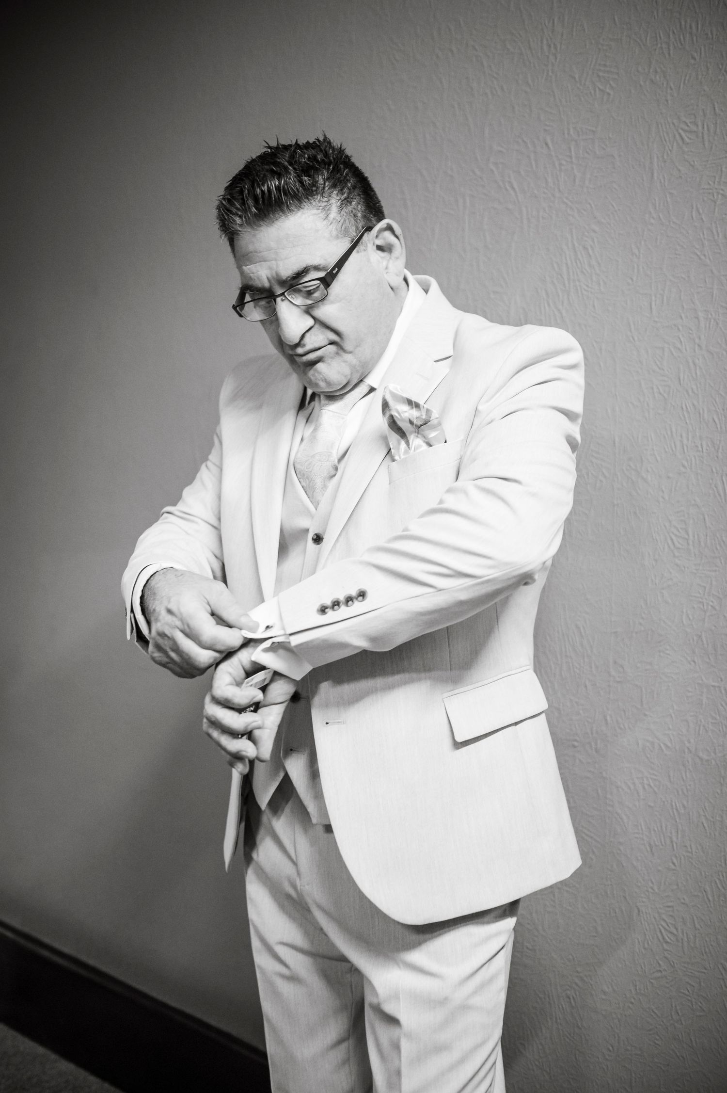 Series of black and white photos showing someone adjusting cufflinks while wearing a white suit.