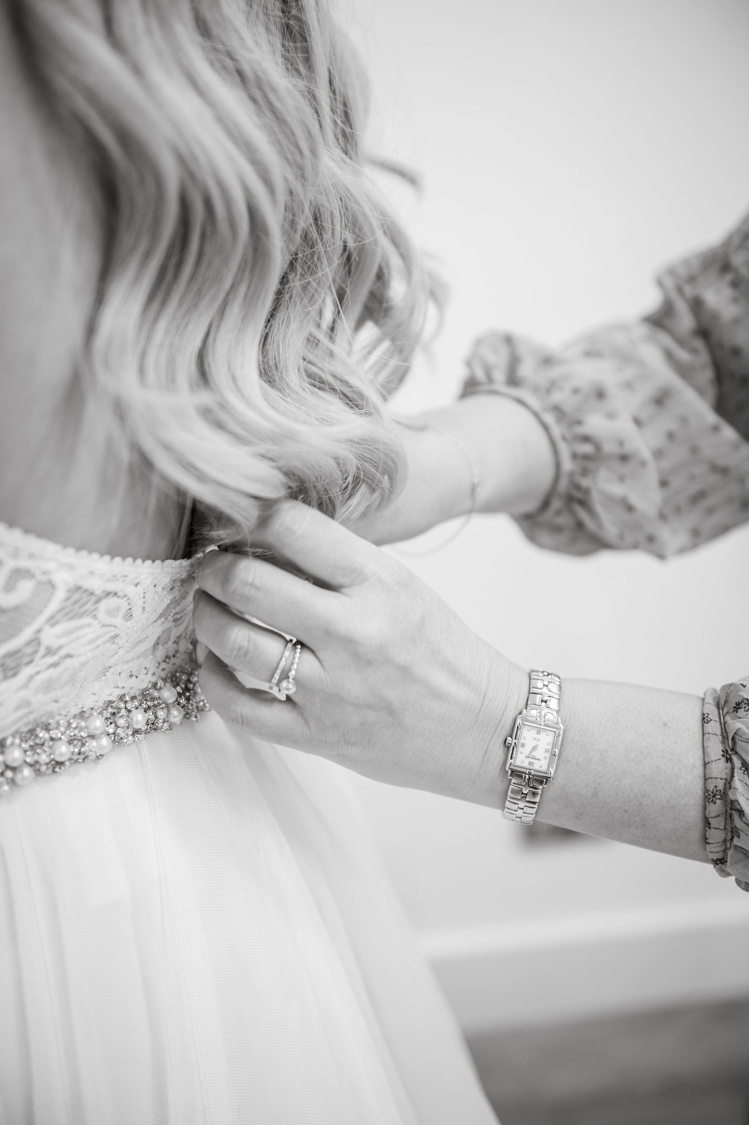 Close-up details of delicate lace and jewelry on a white wedding dress.