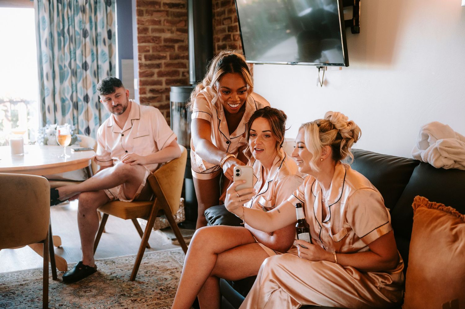 Bridal party getting ready in matching silk robes in a cozy indoor setting.