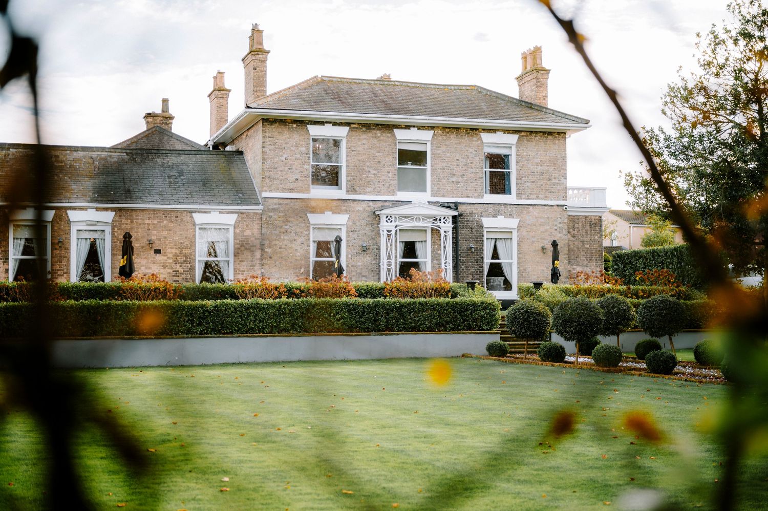 Elegant country house with manicured lawn and traditional Georgian architecture.