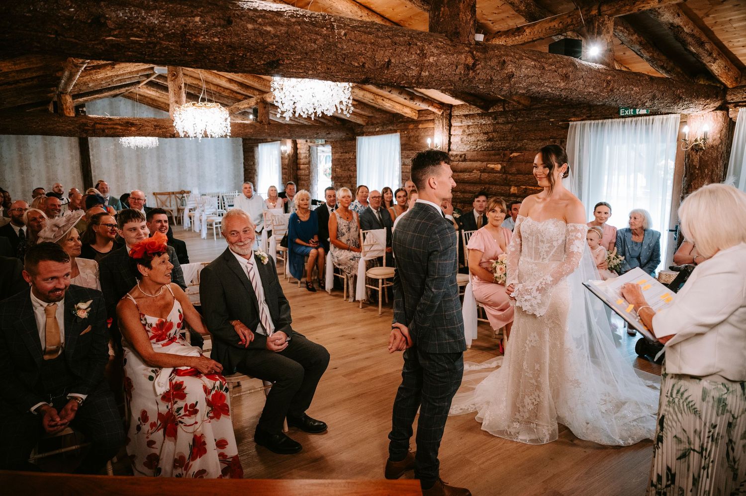 Wedding reception in rustic wooden venue with exposed beams and warm lighting.