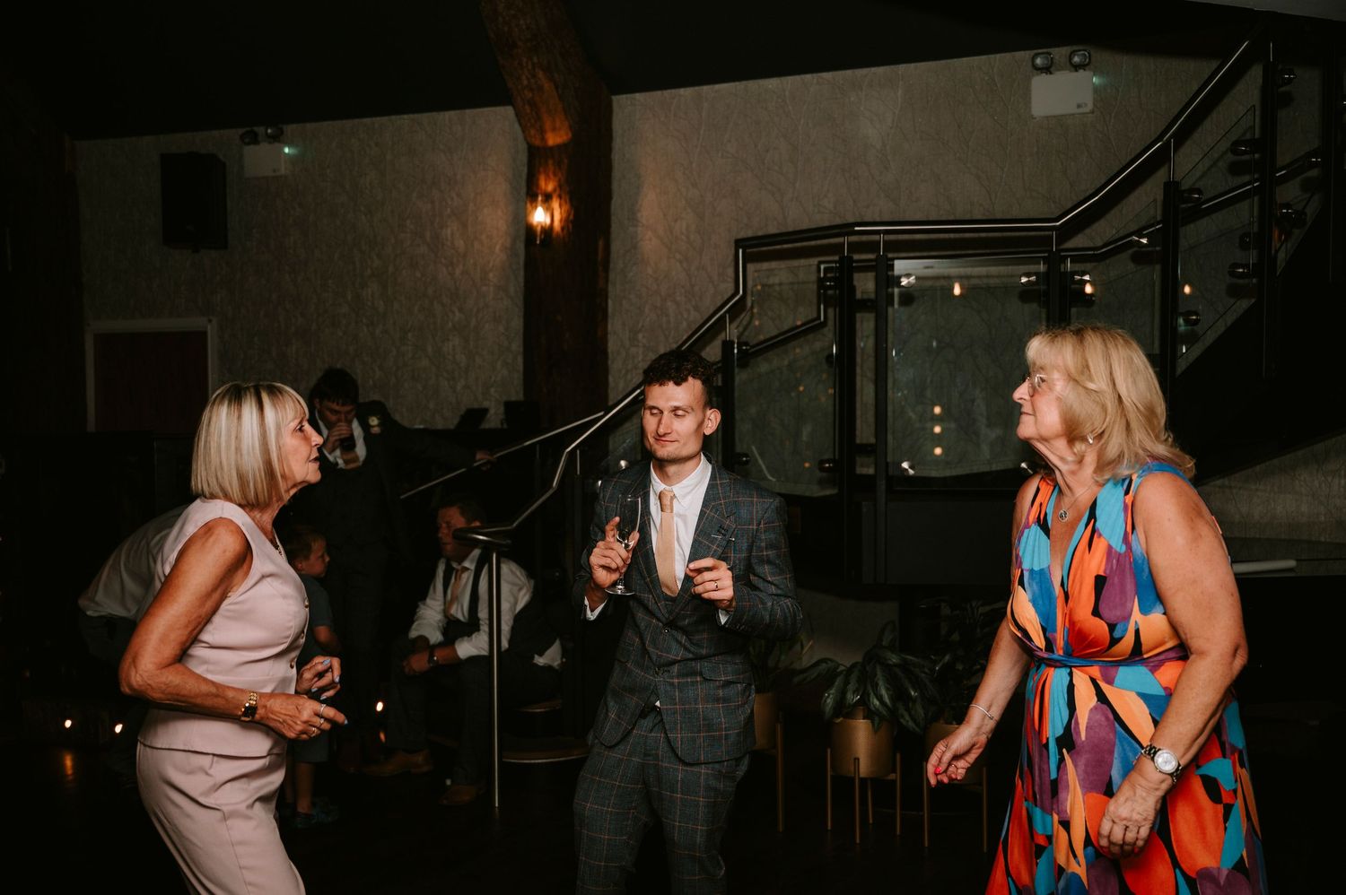 Wedding guests dancing and socializing at evening reception party.