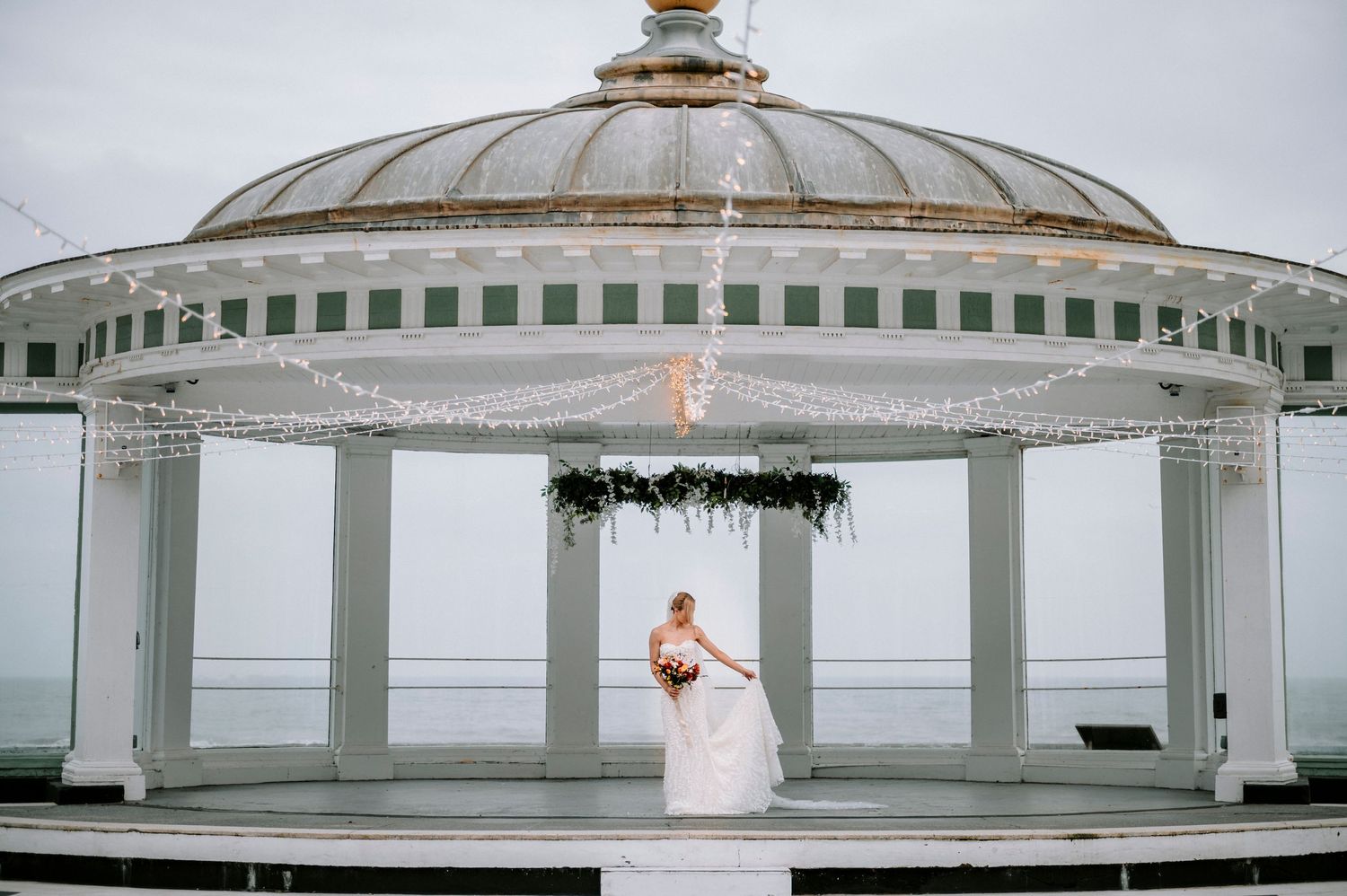 Architectural detail of domed wedding venue with white columns and green trim.