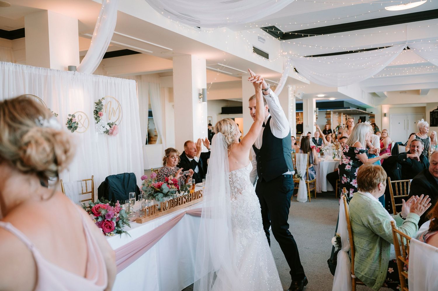Wedding reception venue decorated with white draping and floral arrangements.