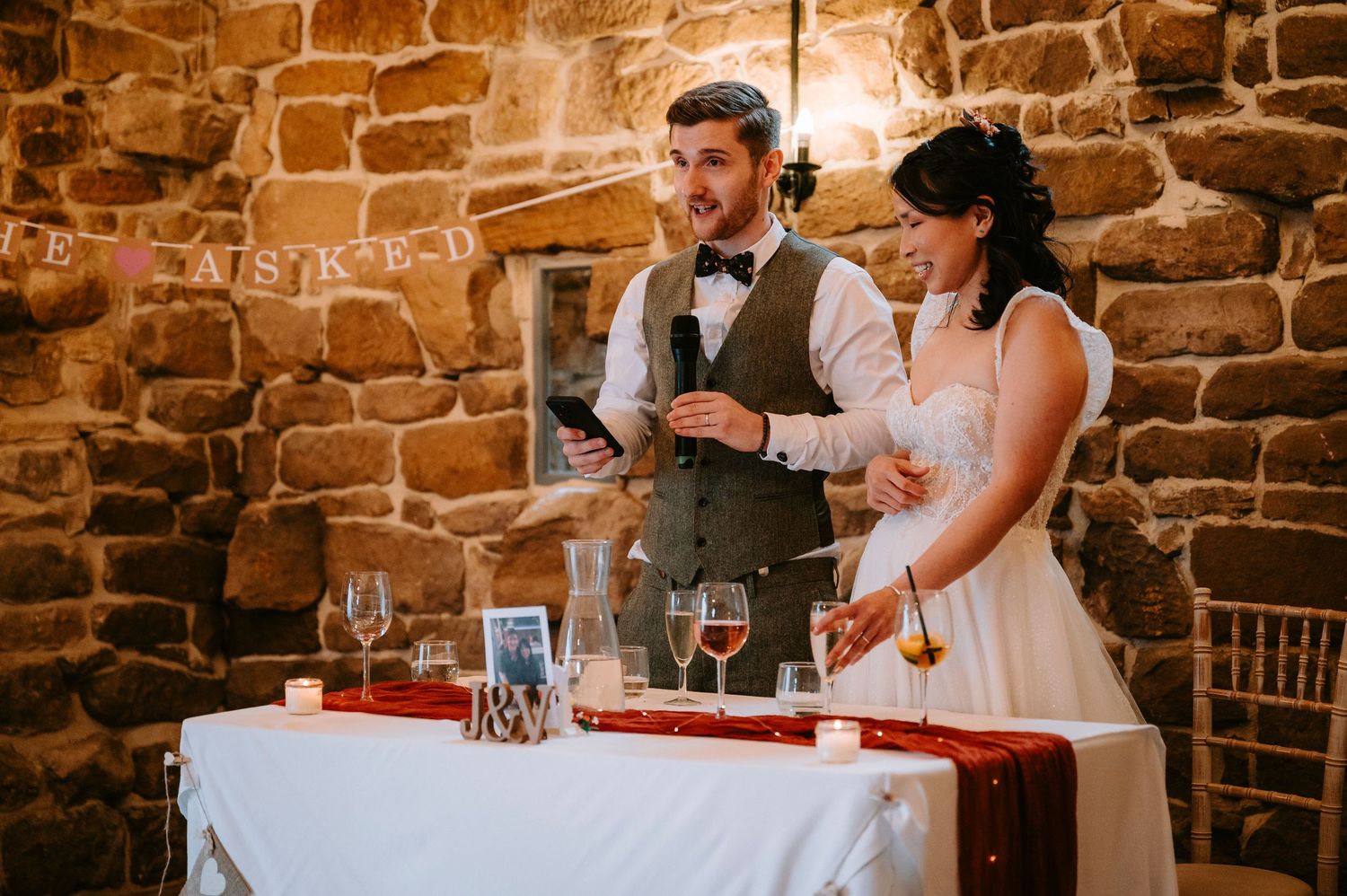 A wedding celebration in progress inside a charming rustic venue with exposed stone walls.