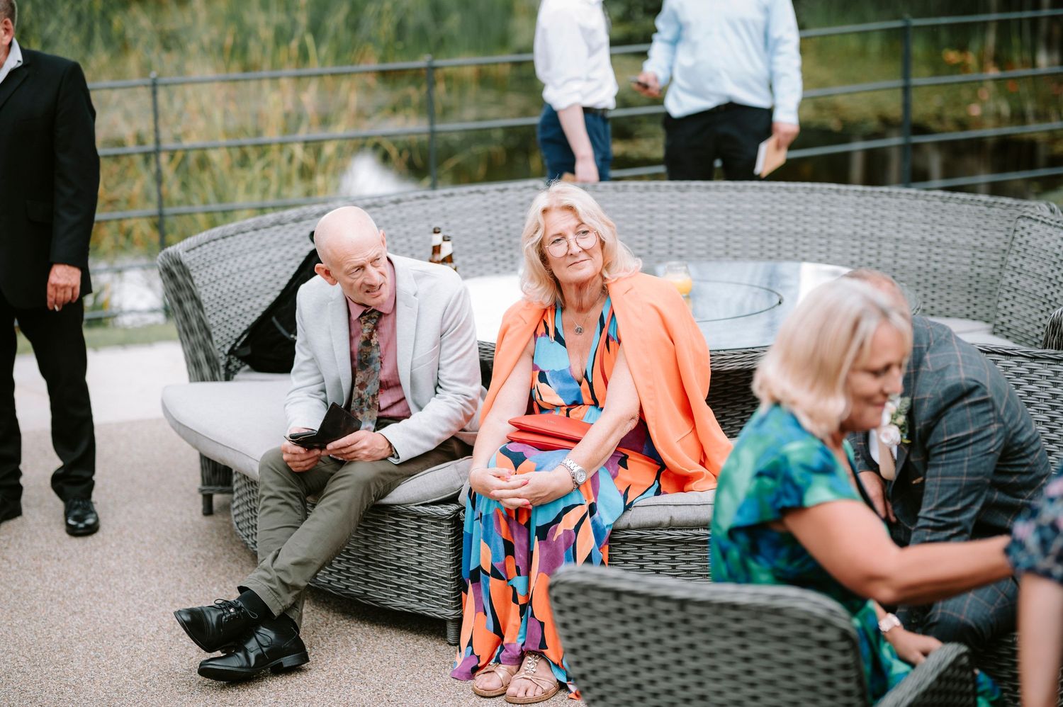 Wedding guests relax on outdoor patio furniture during the reception.