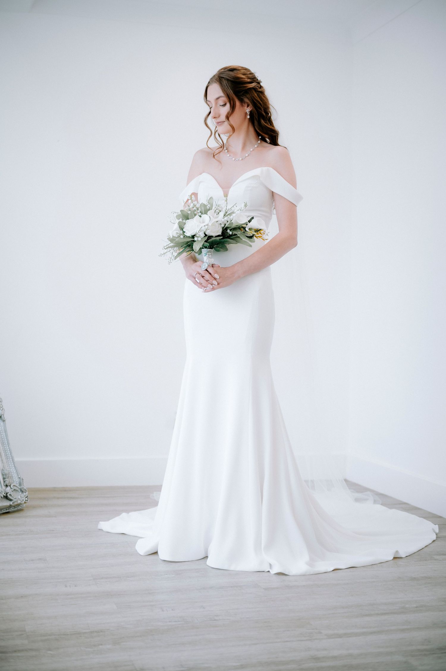Full length view of bride in flowing white wedding dress with bouquet.