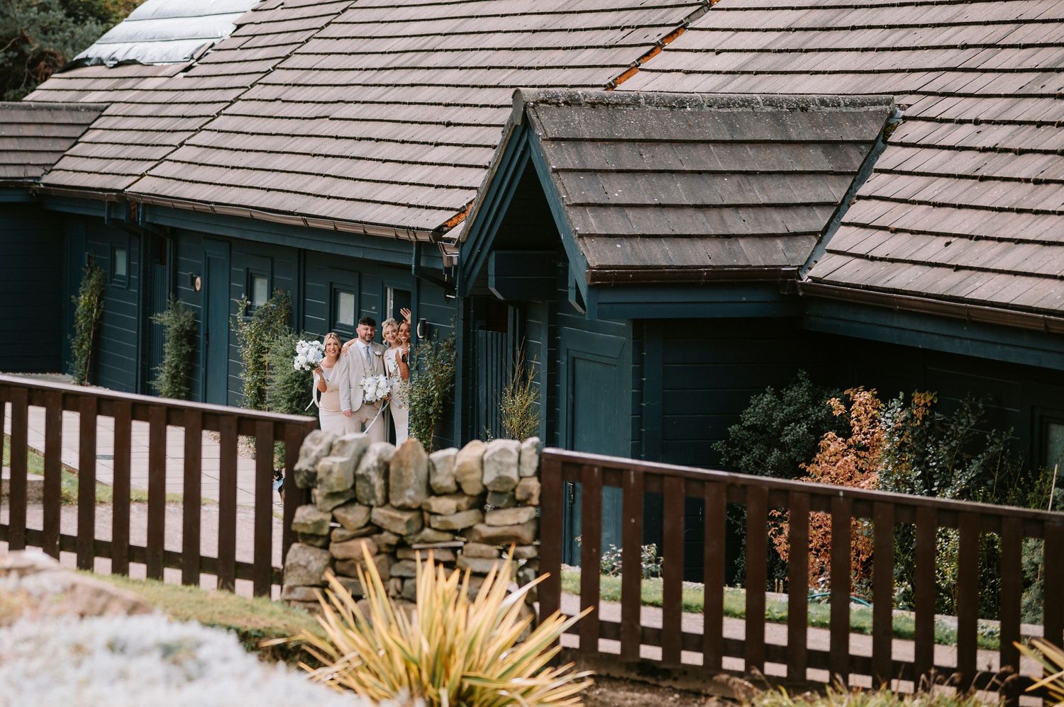 Wooden shingle roofing detail on a rustic cabin with decorative railing and ornamental grasses in the foreground.