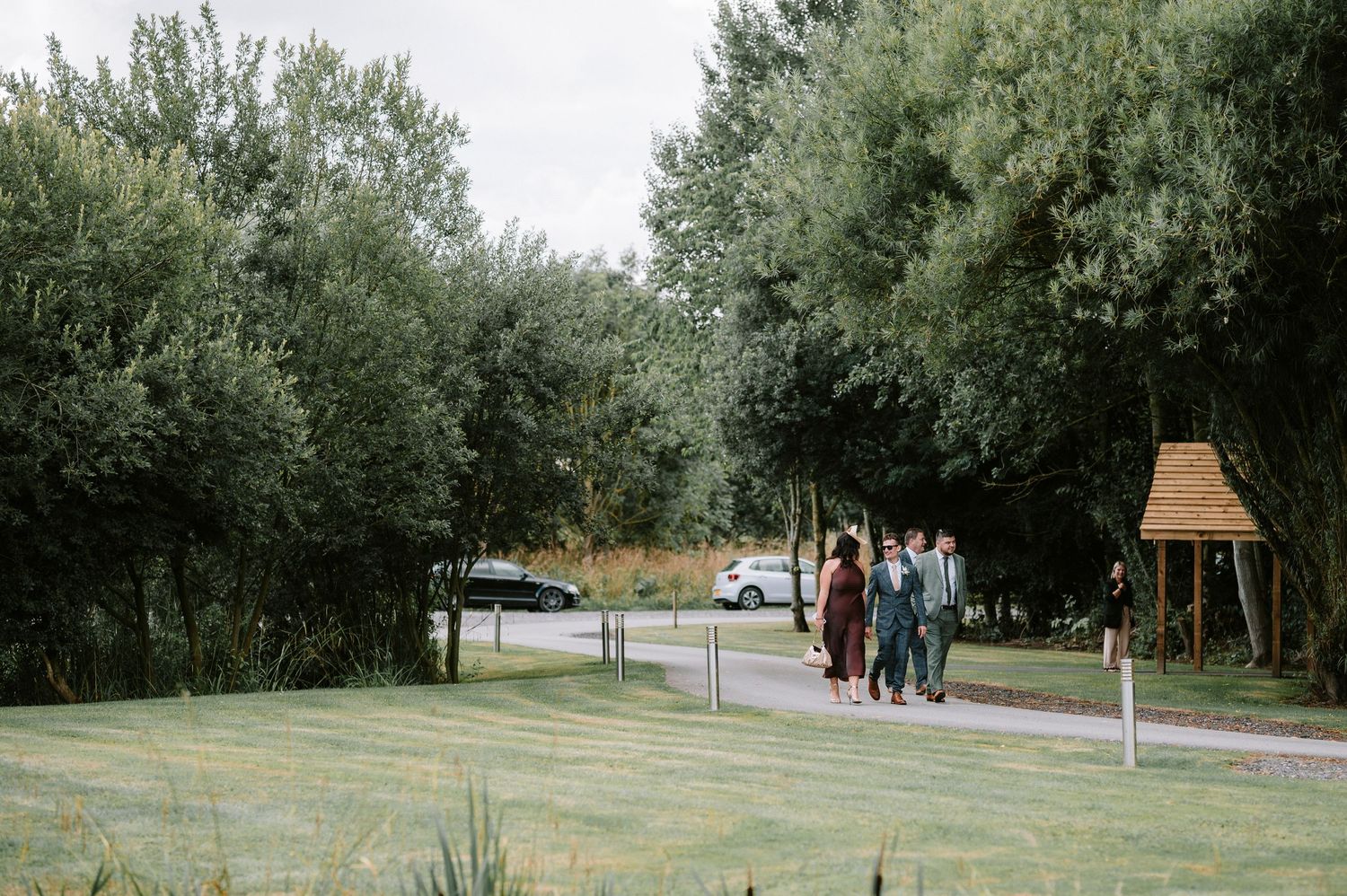 Group walking along tree-lined pathway at outdoor venue.