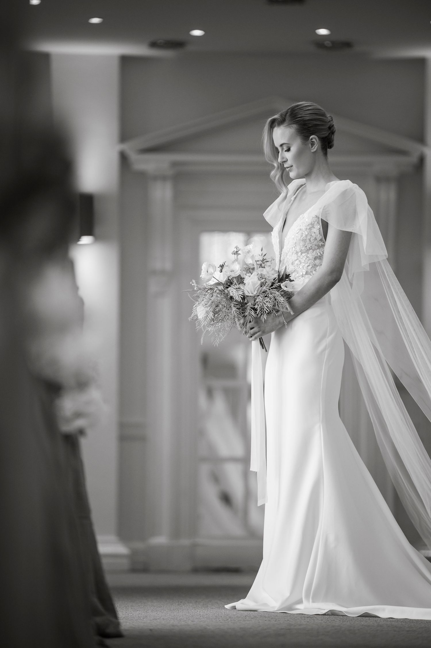 Artistic black and white bridal portrait showcasing flowing veil and bouquet.