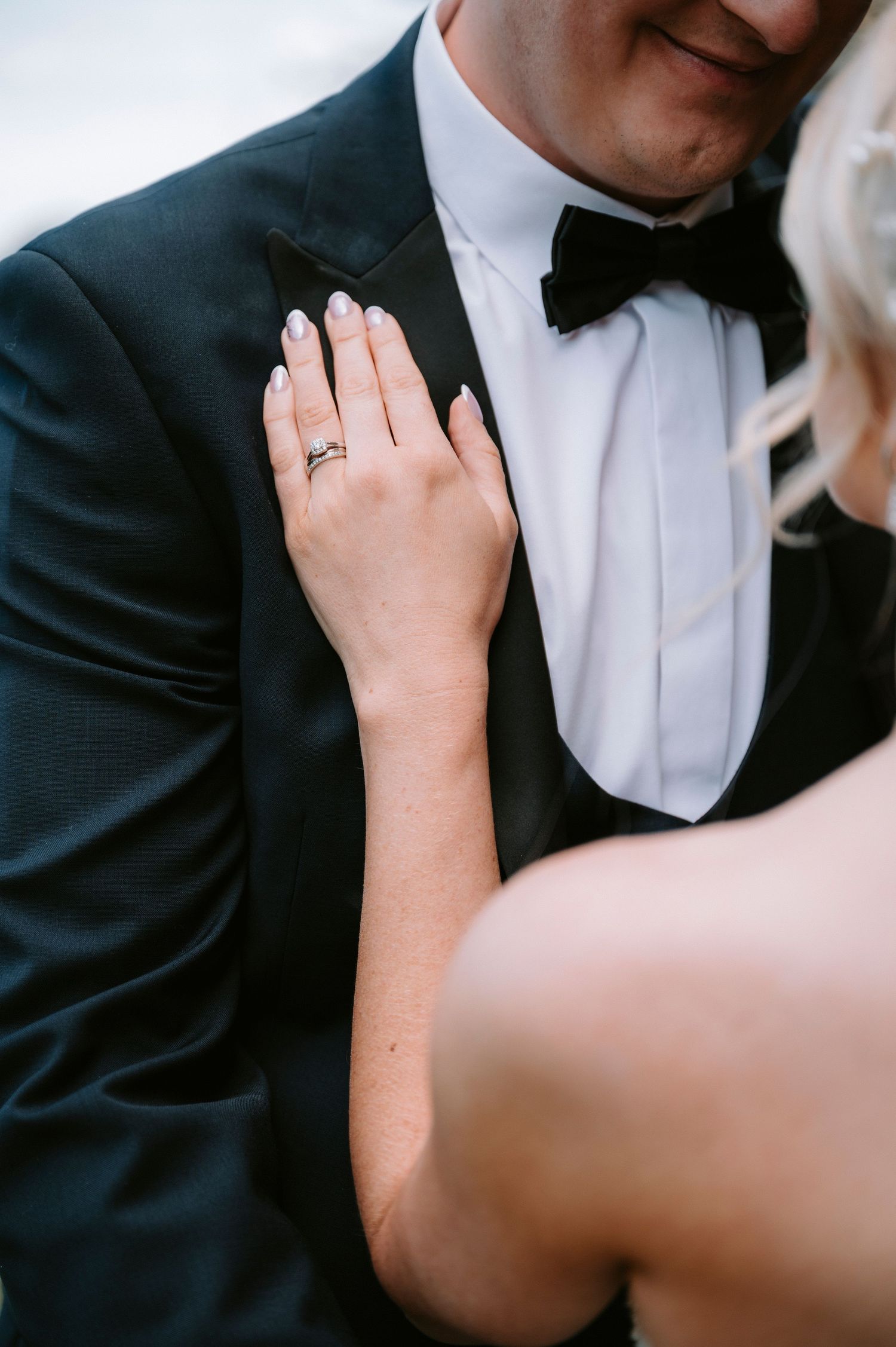 Close-up romantic moment showing wedding ring and formal attire.