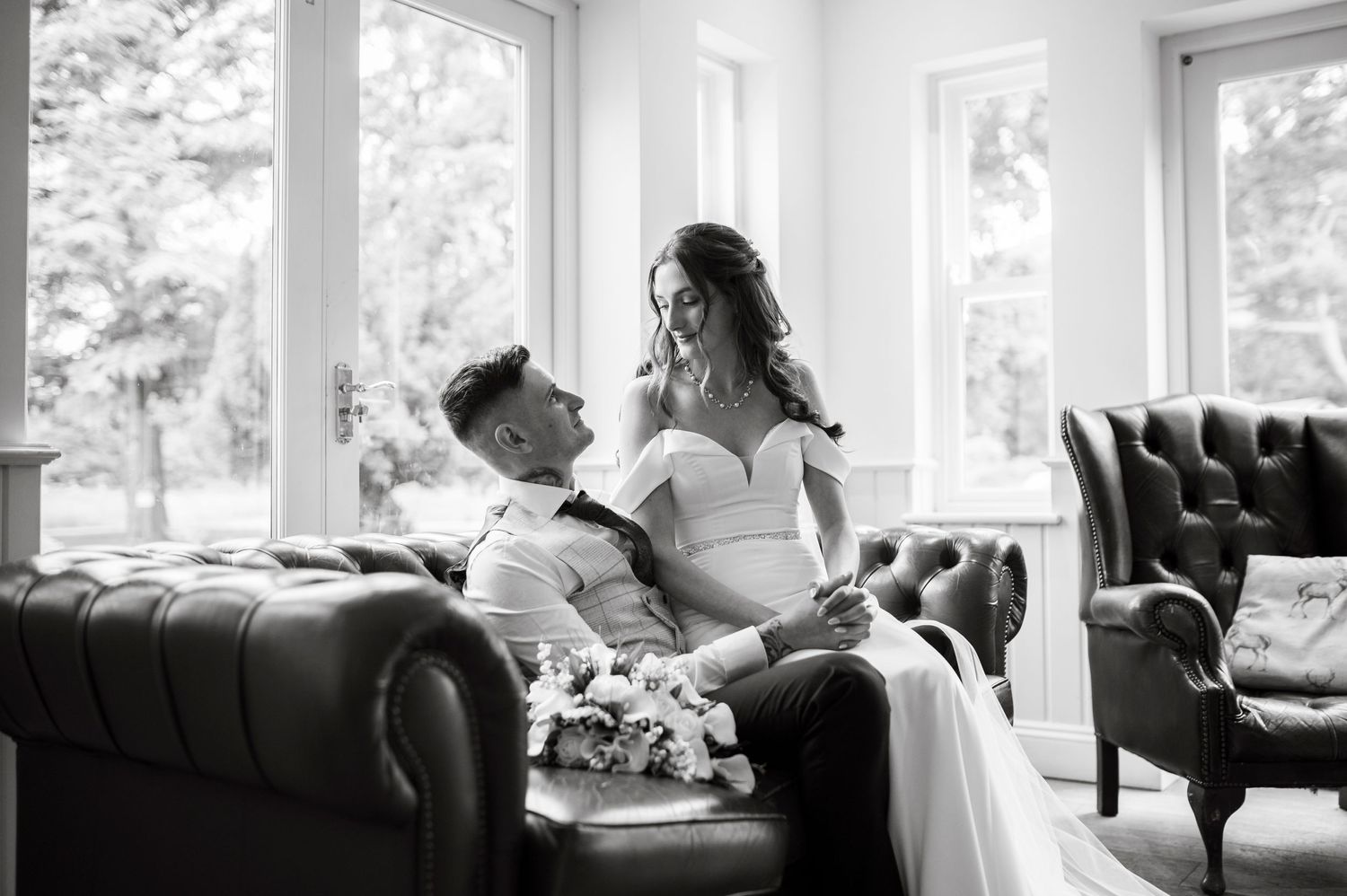 Intimate black and white portrait of couple relaxing on vintage sofa.