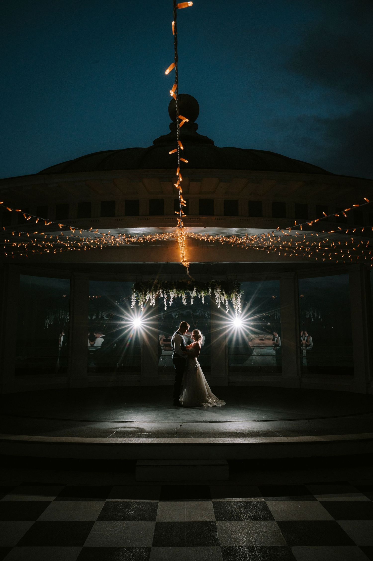 Dramatic nighttime dance scene with string lights and spotlights creating romantic ambiance.