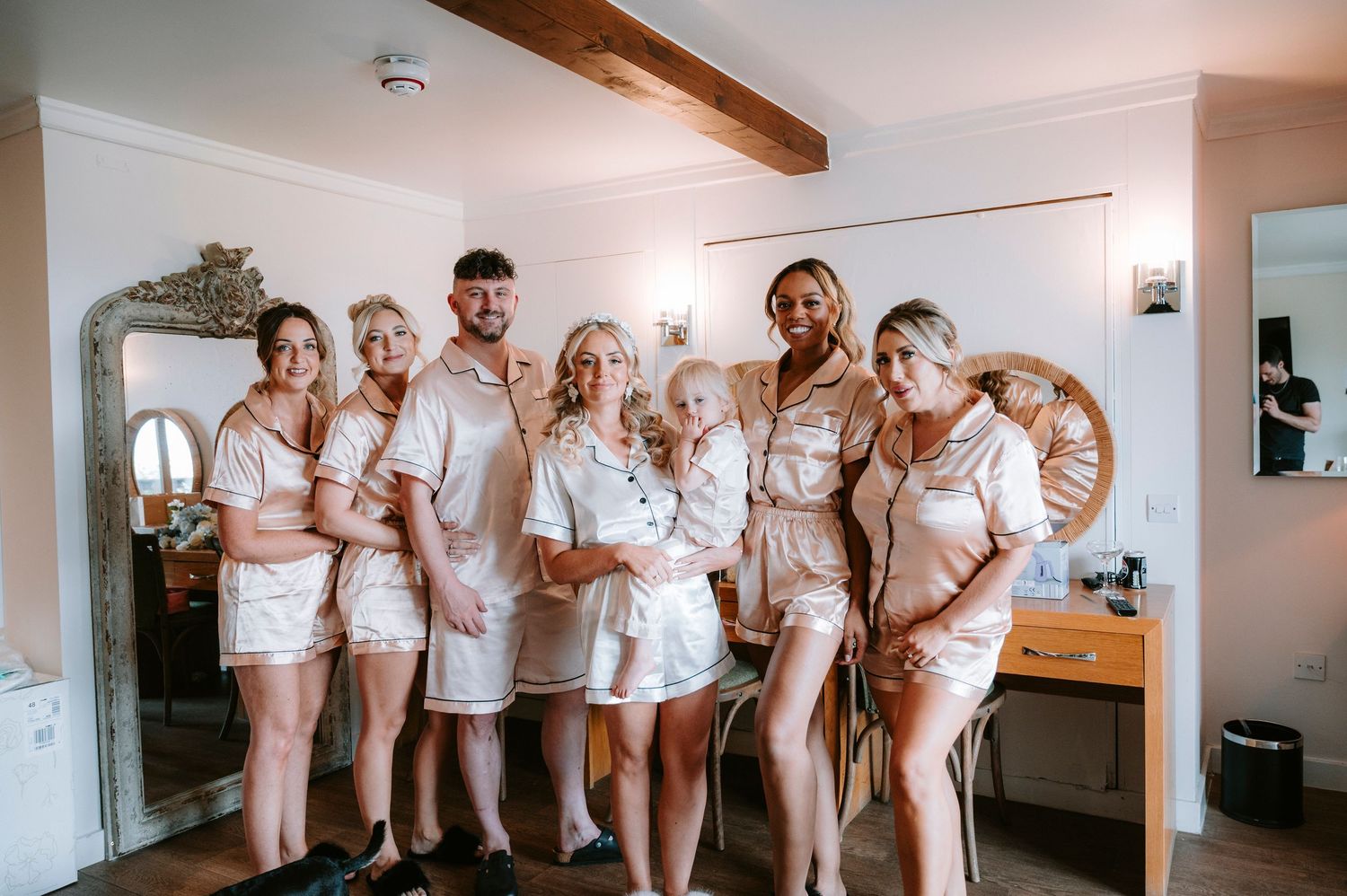 Bridal party in matching white outfits poses together in a bright modern room.