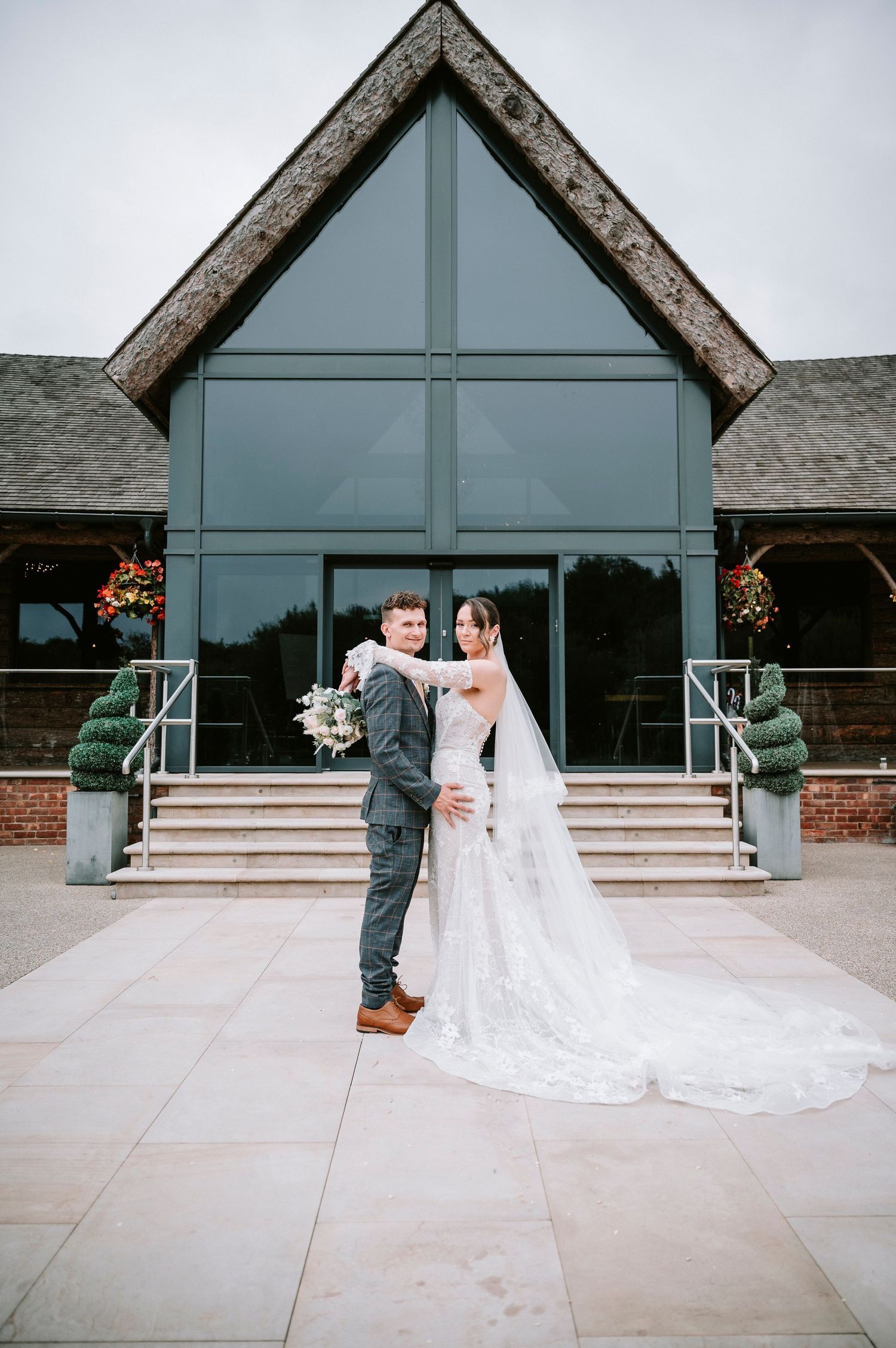 Modern wedding venue exterior with glass facade and concrete steps leading to triangular entrance.