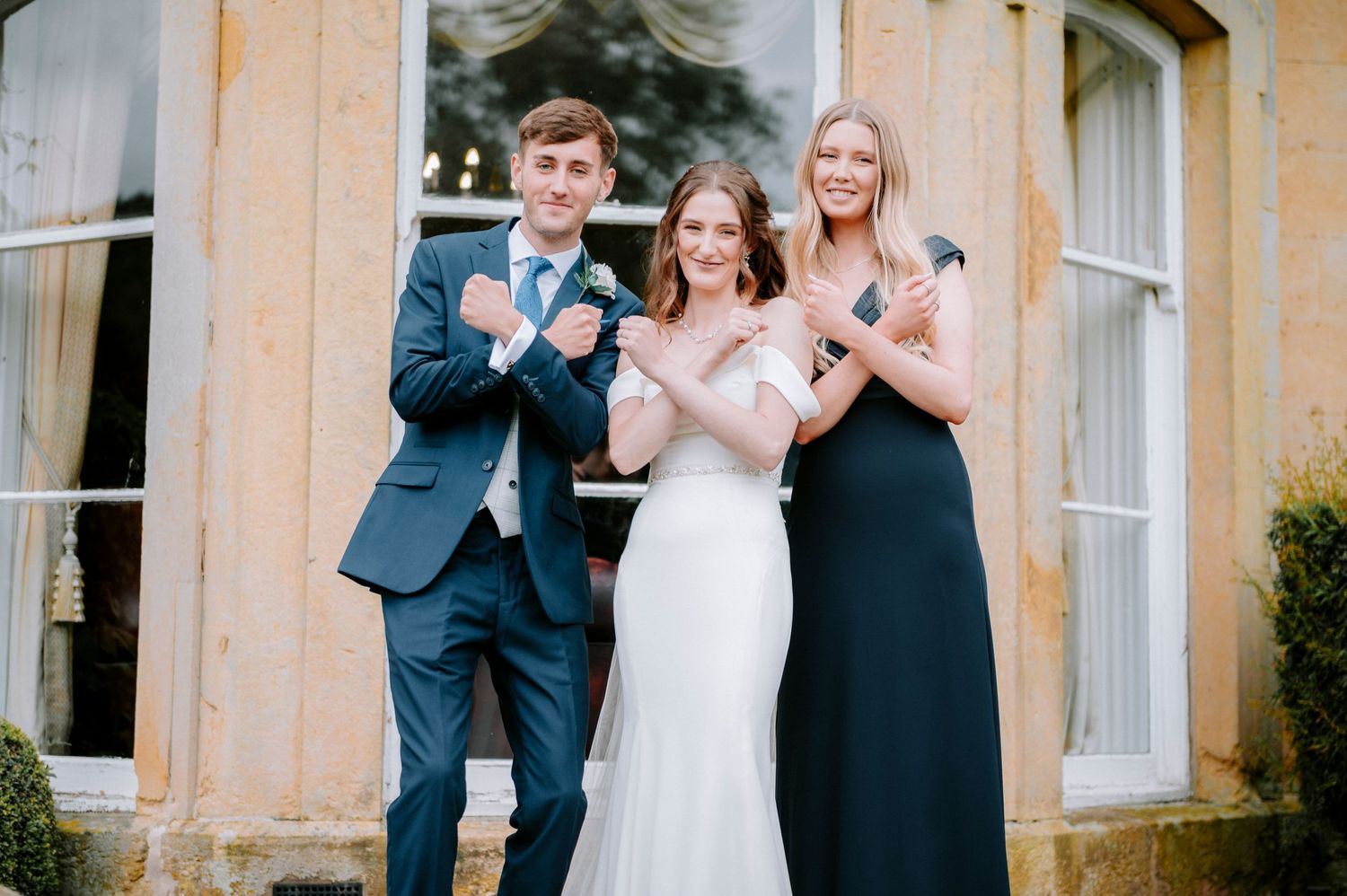 Wedding party celebrates with champagne outside a classic stone building.