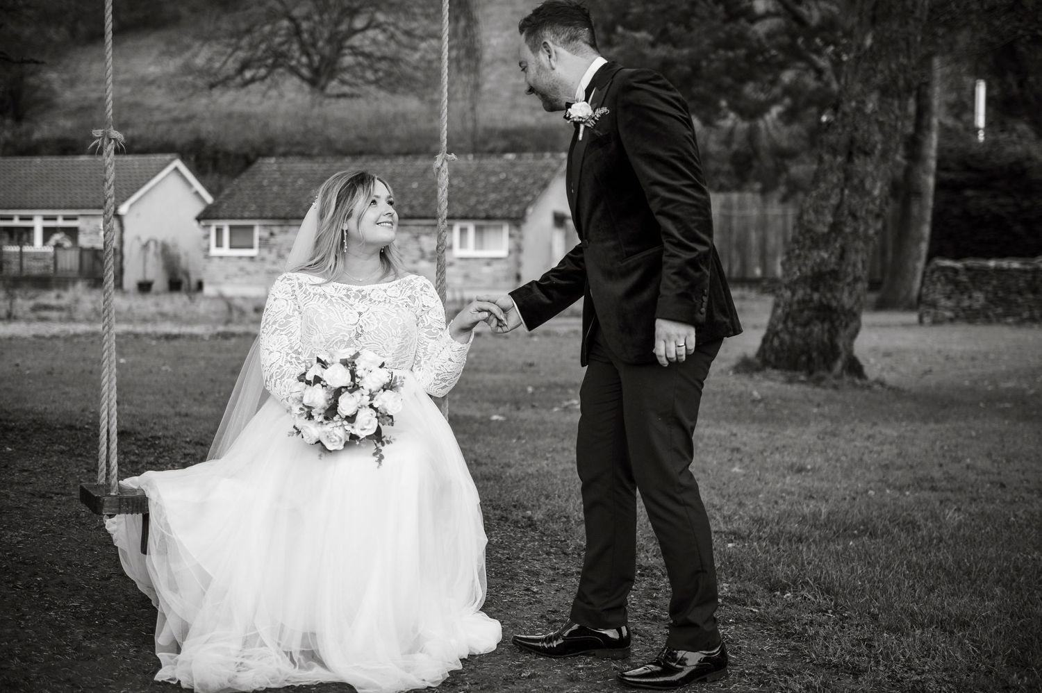A romantic moment shared between newlyweds on a garden swing.