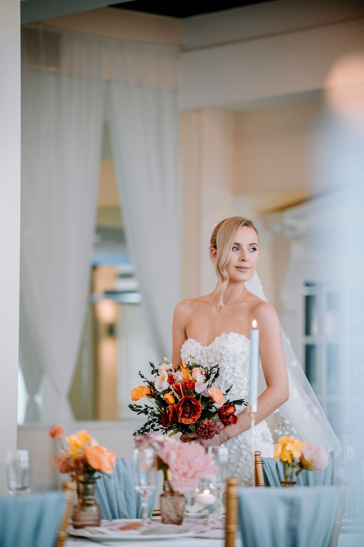 Wedding reception table with coral and blue decor in bright indoor venue.