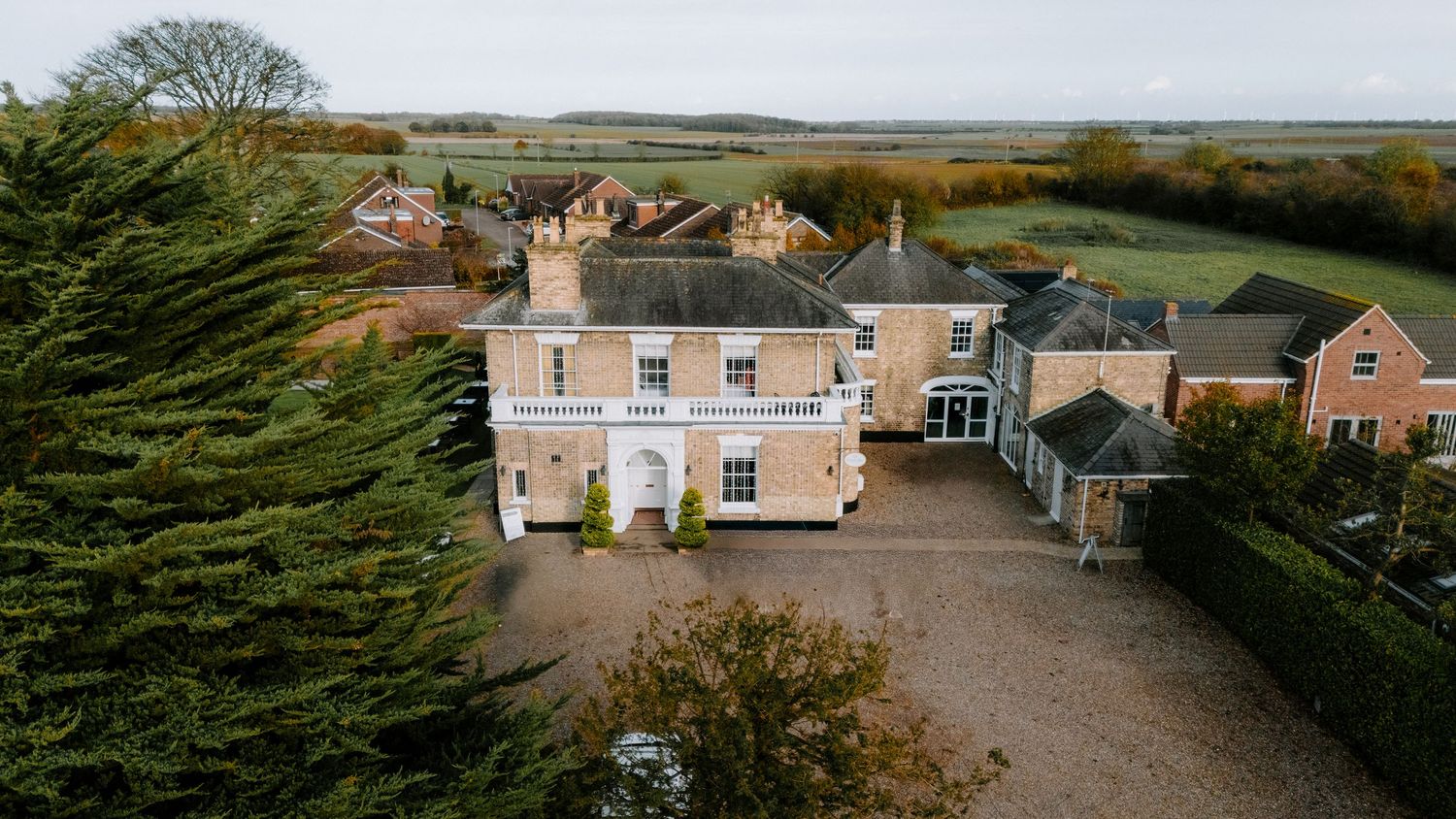 Panoramic view of a country estate with circular driveway and landscaped gardens.